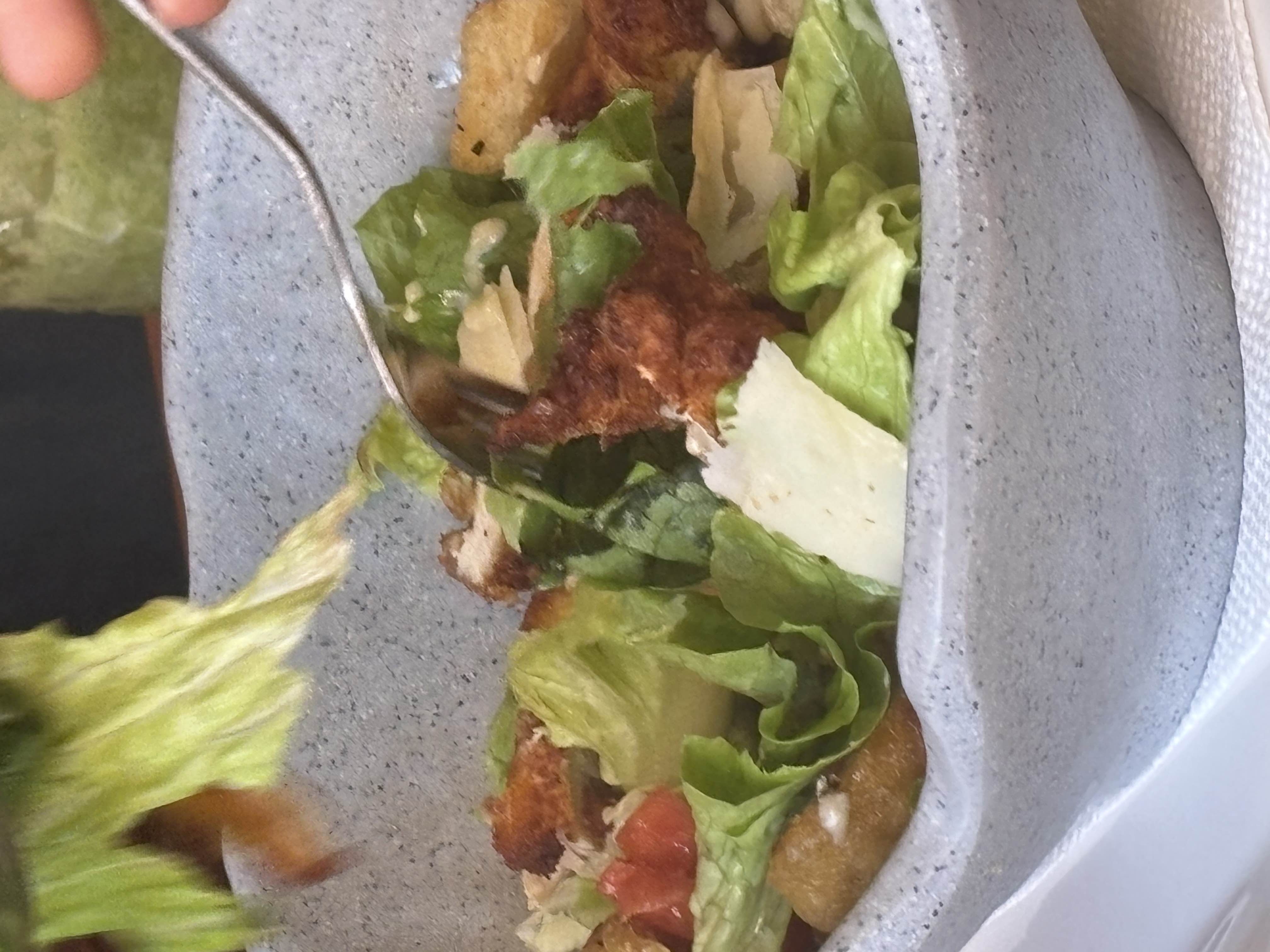 A Caesar salad with lettuce, croutons, parmesan cheese, grilled chicken, and Caesar dressing.