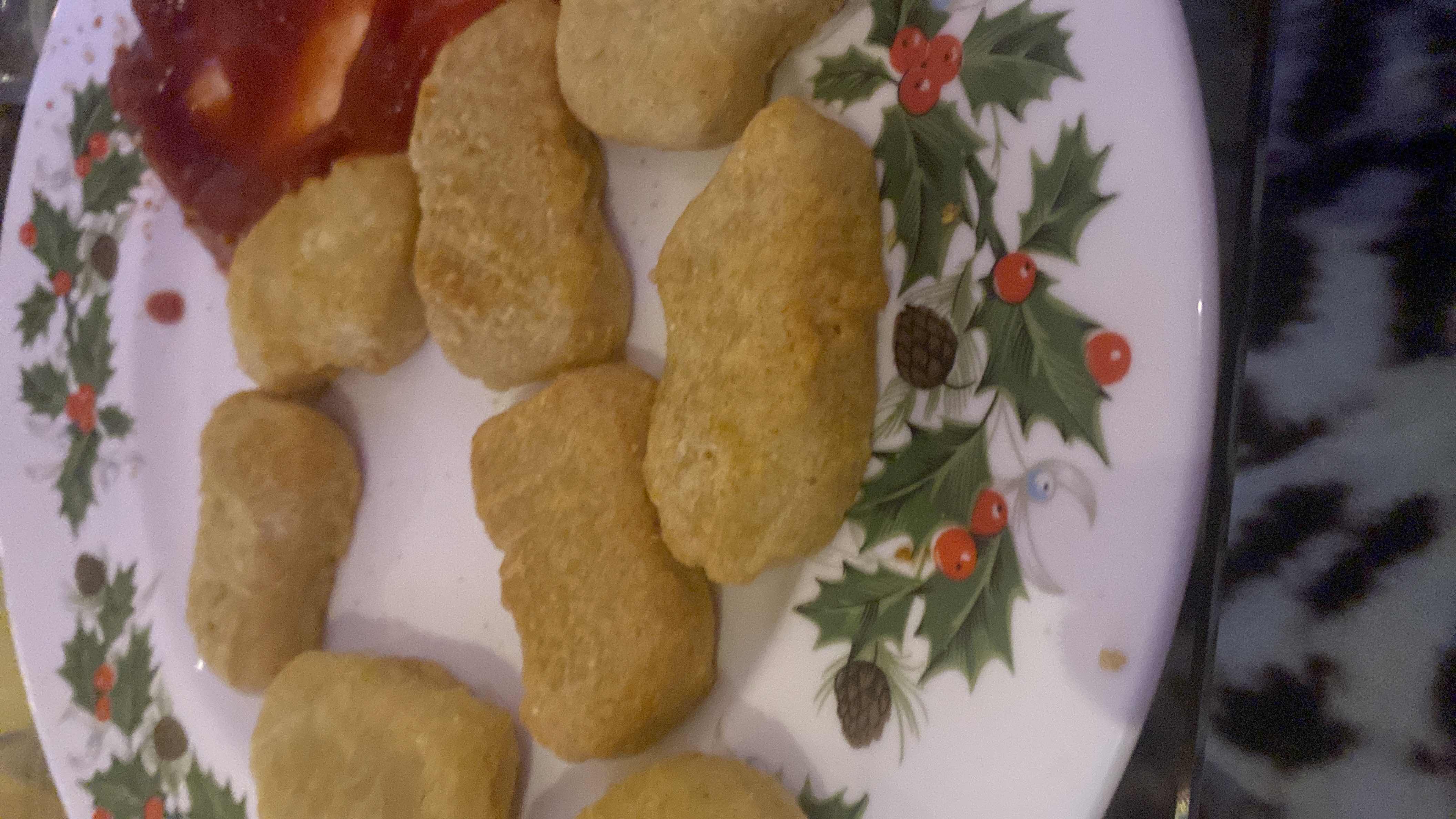 The image shows a plate of chicken nuggets served with ketchup, providing a moderate amount of calories, protein, carbs, and fats.