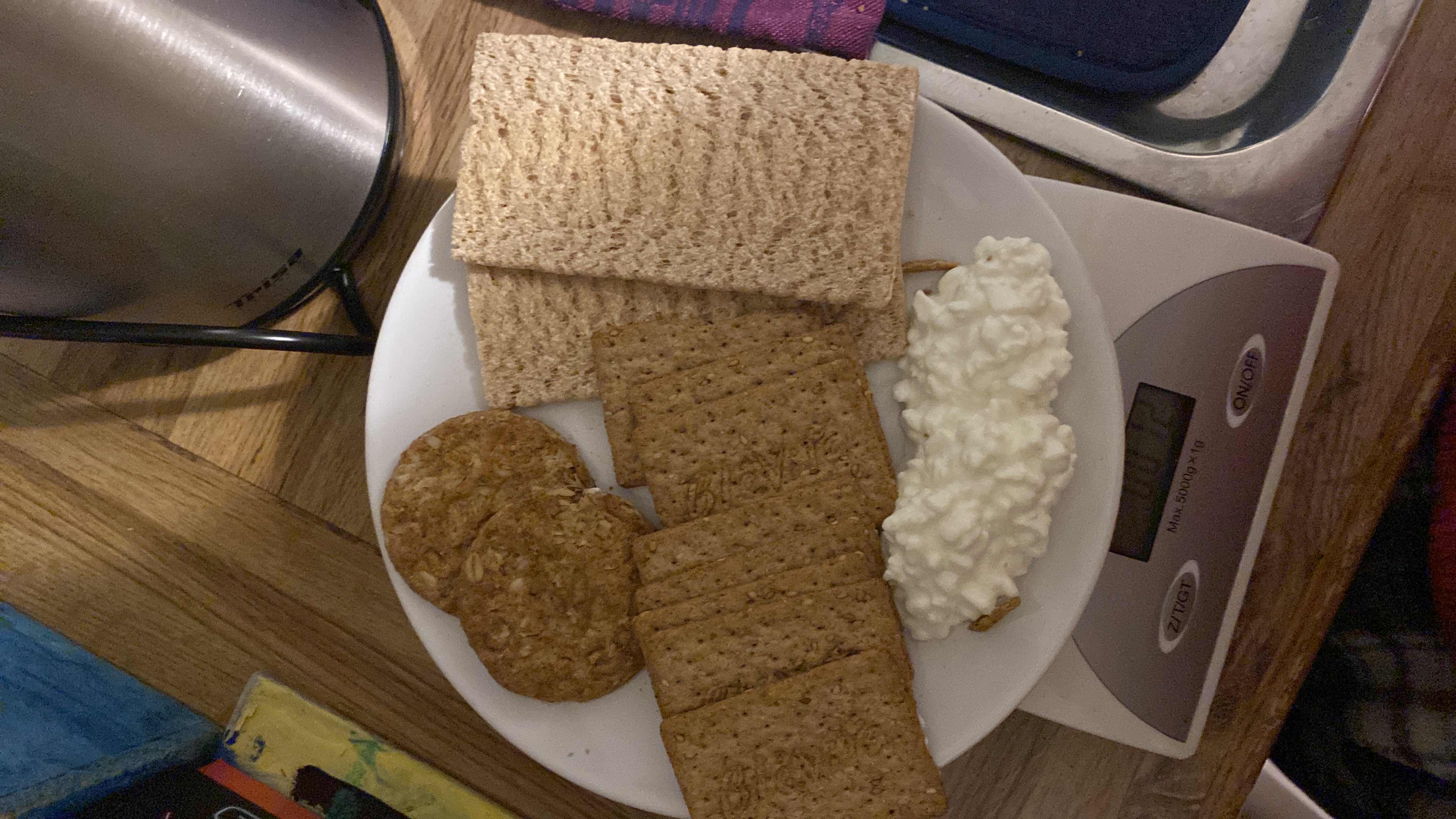 A plate containing cottage cheese, whole grain crackers, and crispbread, providing a balanced mix of protein, carbs, and fats.