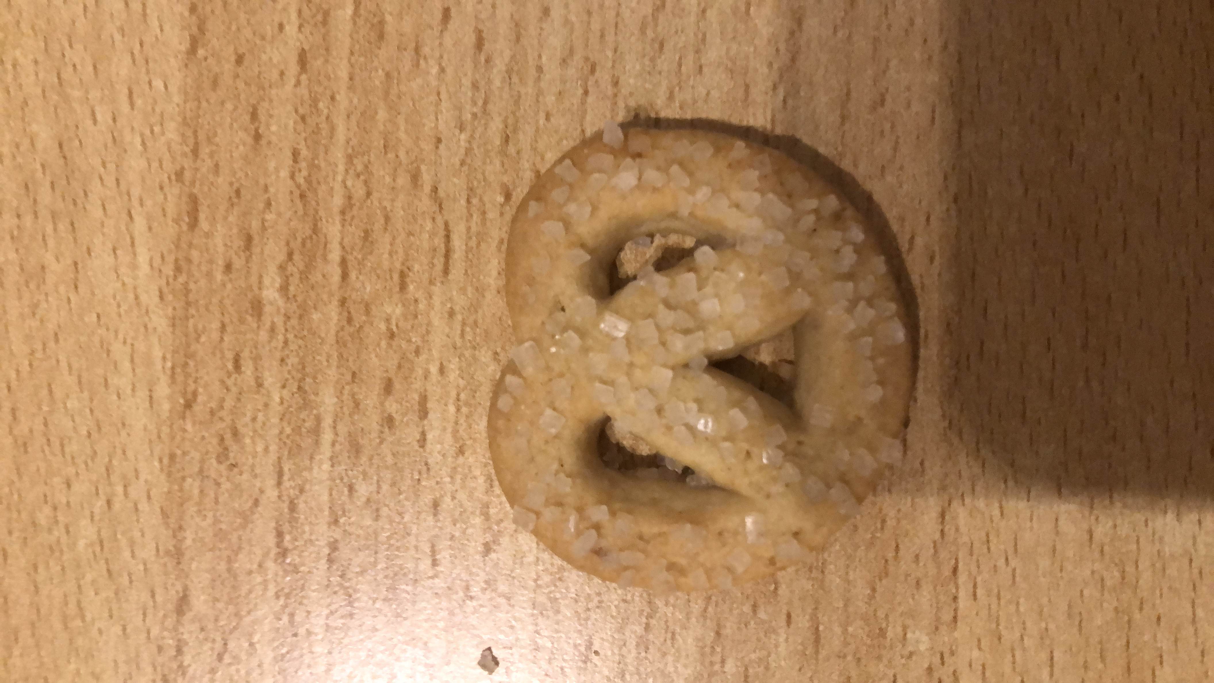 A small sugar-coated pretzel-shaped cookie with moderate calories and low protein content.