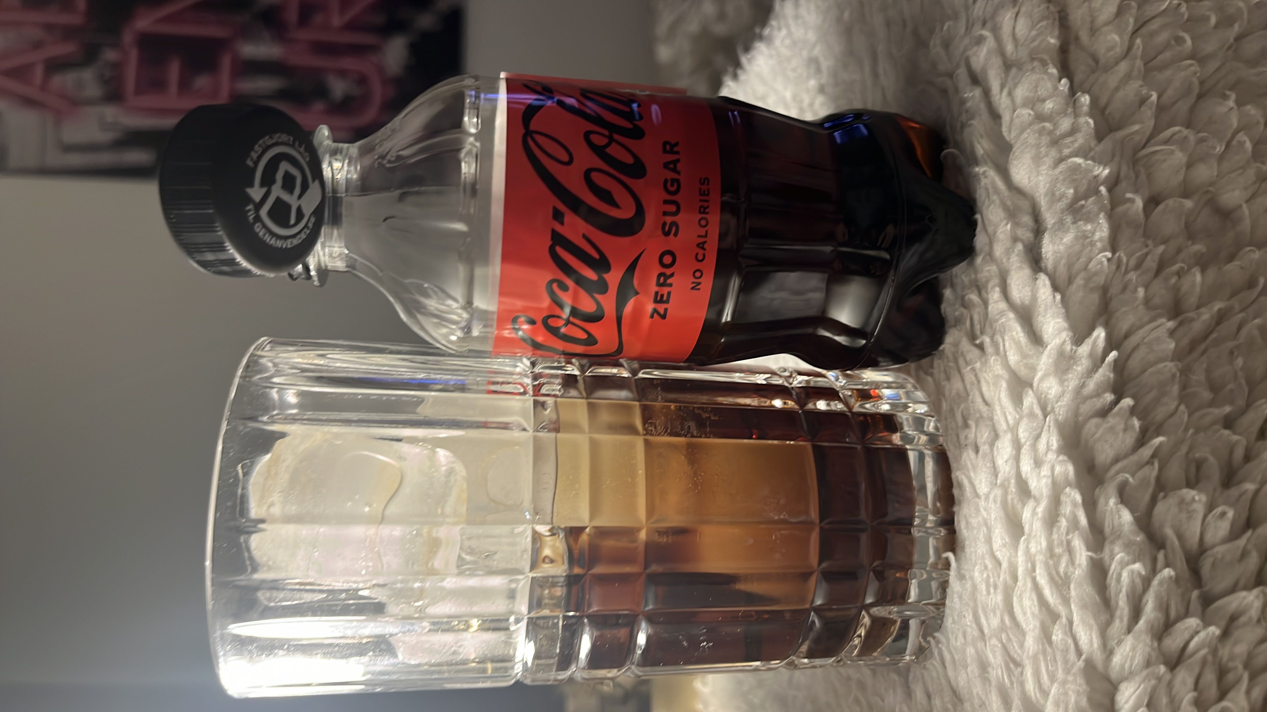The image shows a bottle of Coca-Cola Zero Sugar and a glass with the beverage, which contains no calories, fats, carbs, or protein.