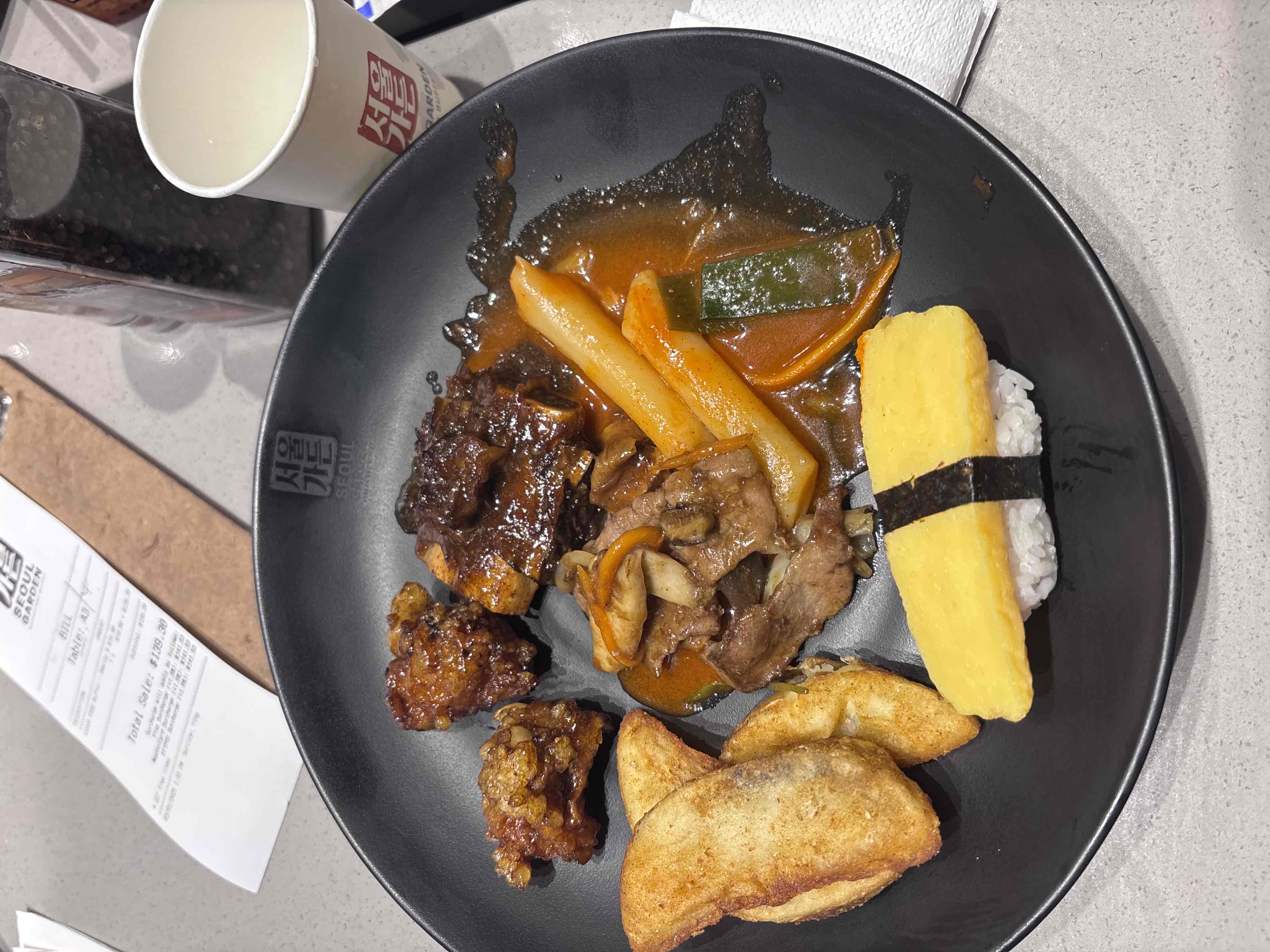 A Korean-inspired dish featuring fried dumplings, egg sushi, braised short ribs, spicy rice cakes, and fried chicken.