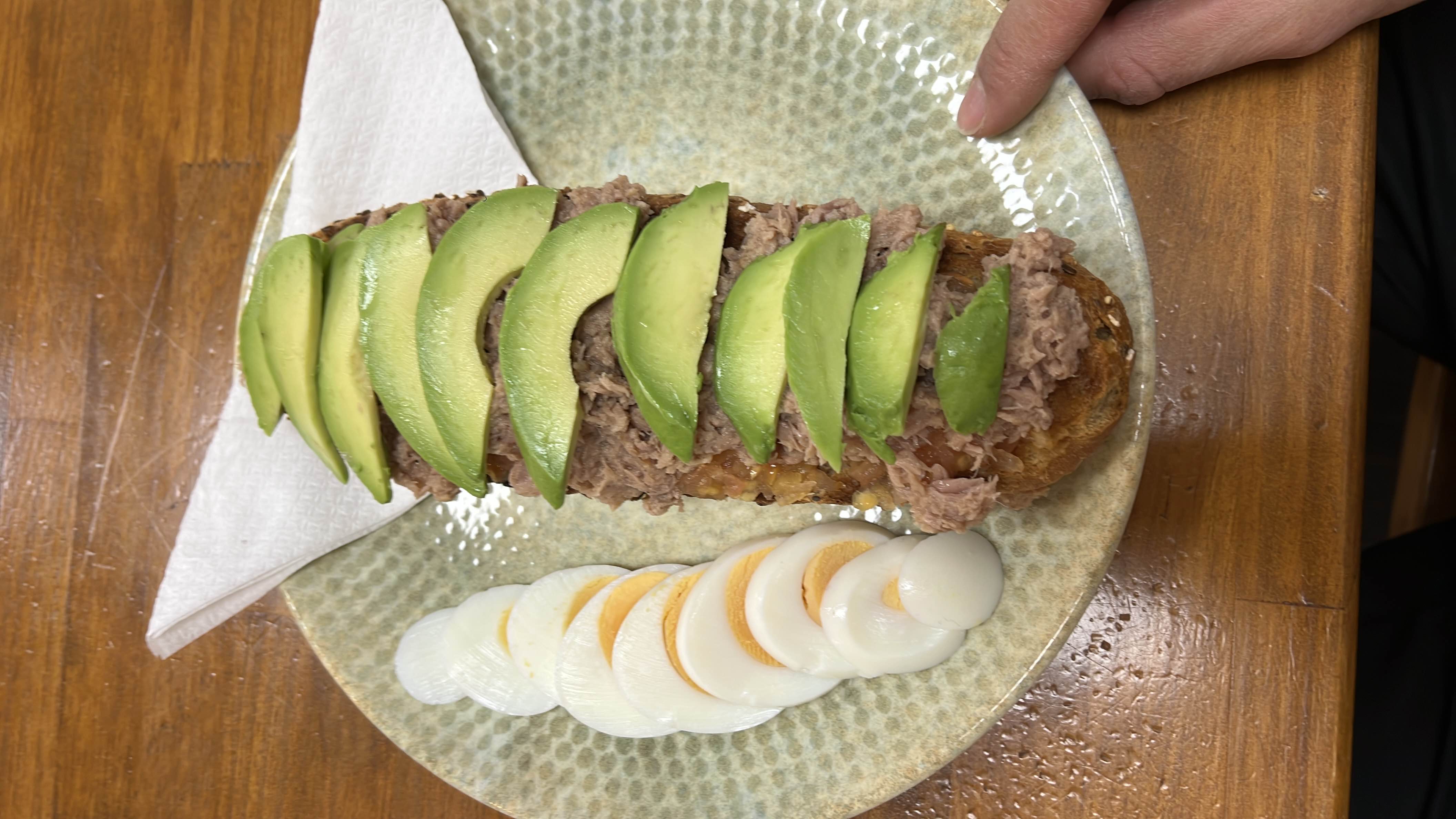 A nutritious meal consisting of avocado slices, tuna, boiled egg, and toast, providing a balanced mix of protein, healthy fats, and carbohydrates.