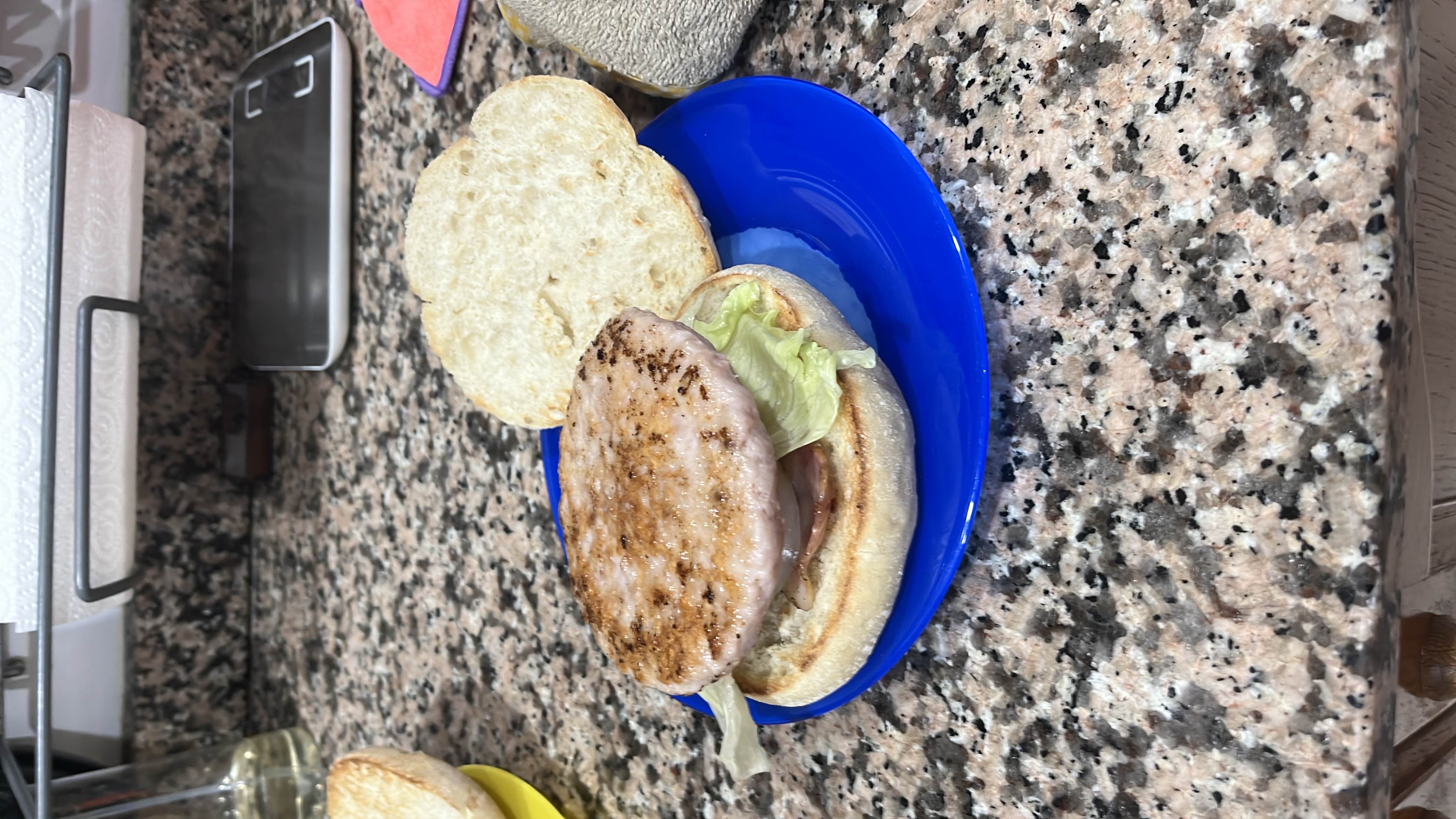 A homemade burger with a grilled patty, lettuce, onion, and tomato served on a bun.