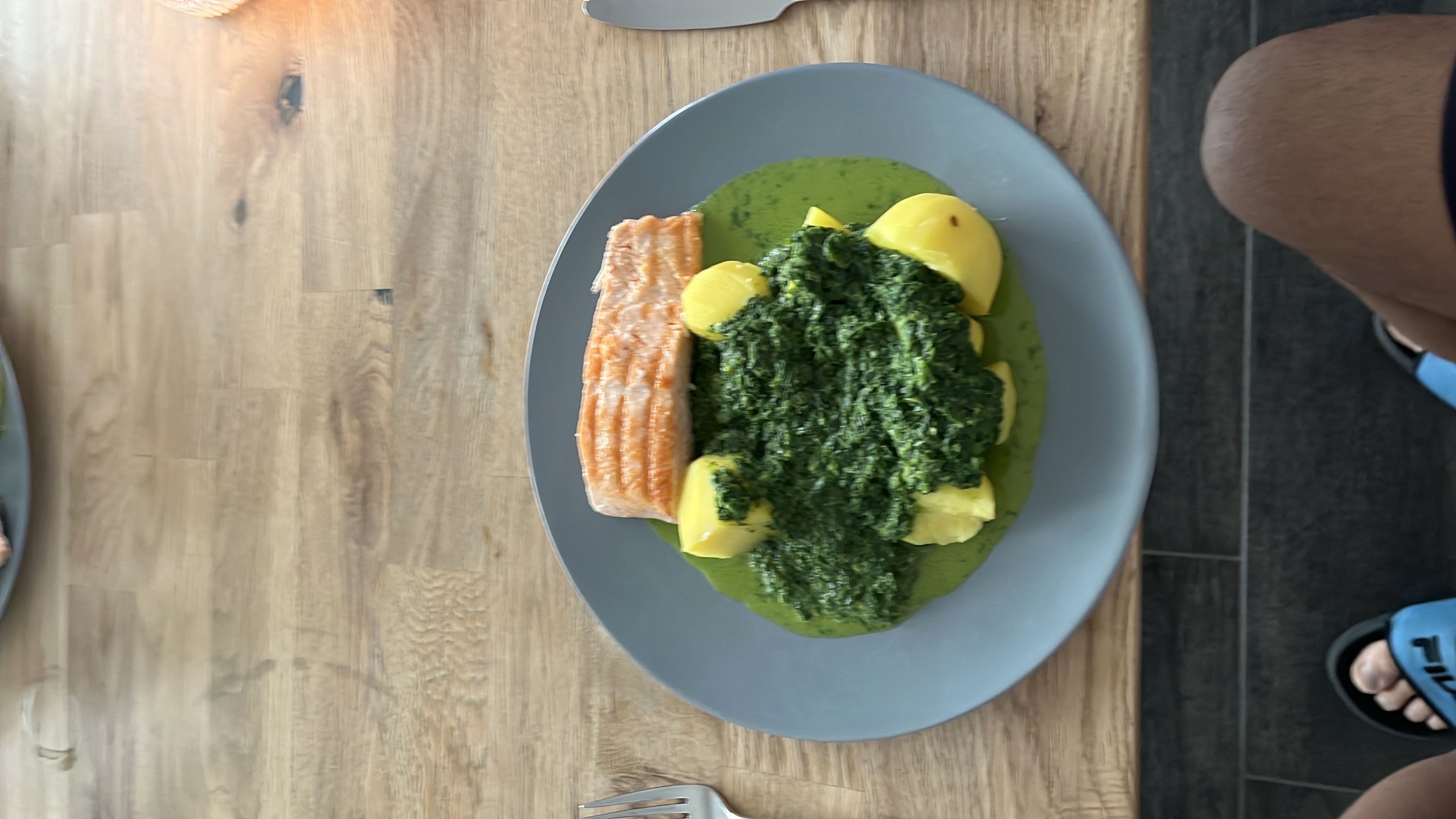 A balanced meal consisting of grilled salmon, boiled potatoes, and spinach sauce, providing a good mix of protein, carbs, and healthy fats.