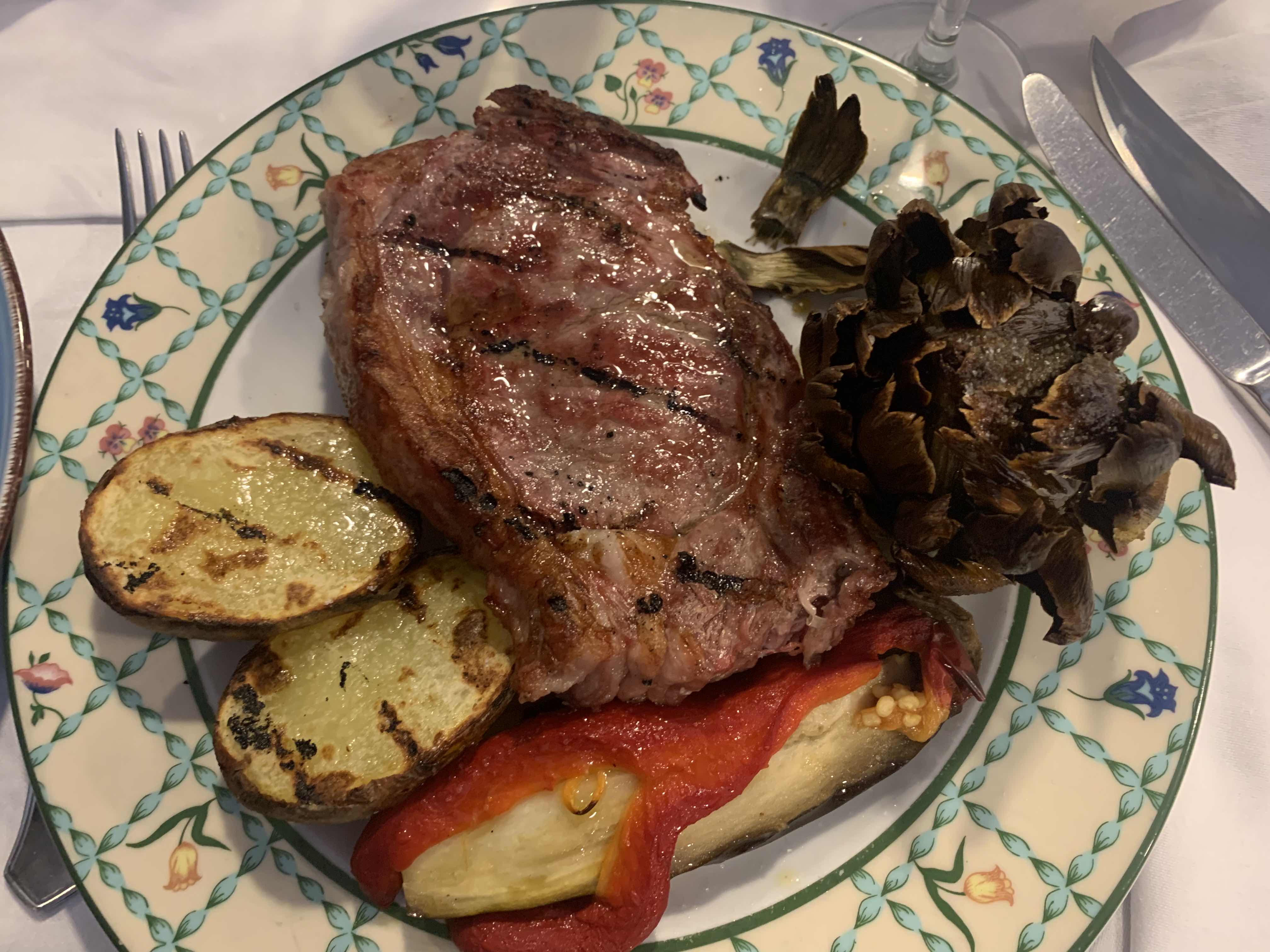 A balanced meal featuring grilled steak, potatoes, red pepper, and artichoke, providing a mix of protein, carbs, and fats.