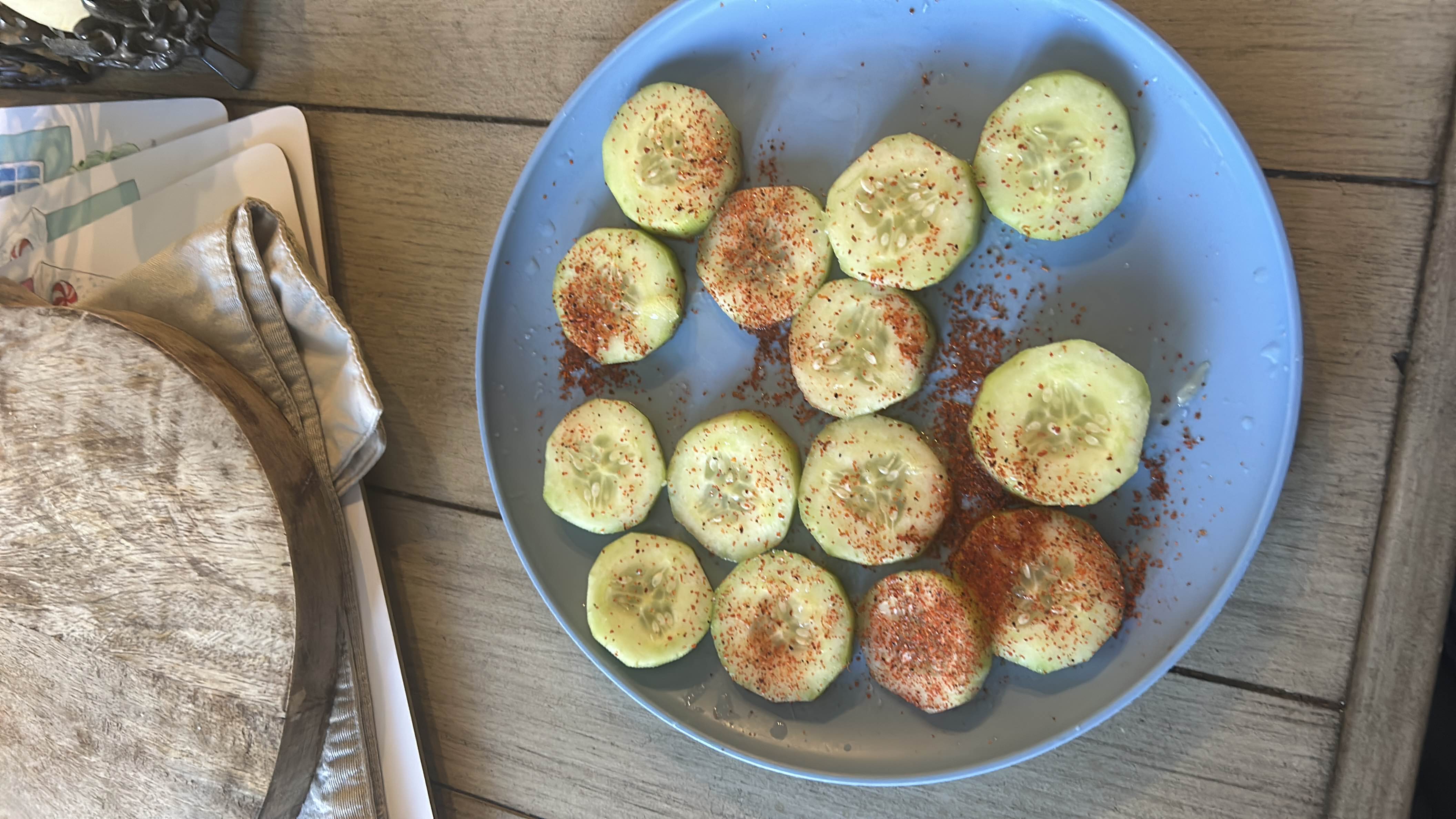 A plate of sliced cucumbers seasoned with chili powder, offering a low-calorie, nutrient-rich snack.