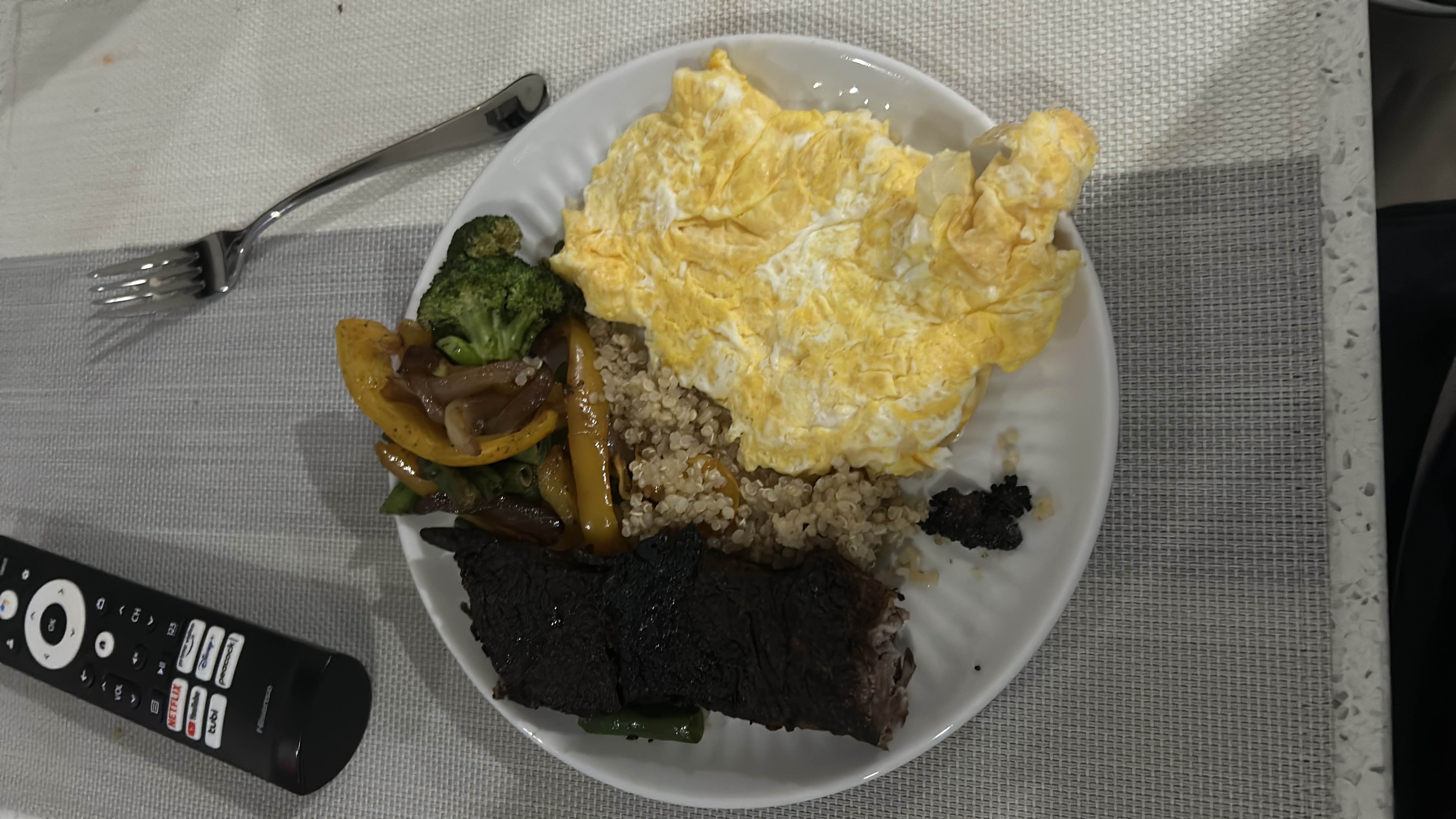 A balanced meal consisting of scrambled eggs, quinoa, grilled vegetables, and beef, providing a good mix of protein, carbs, and fats.