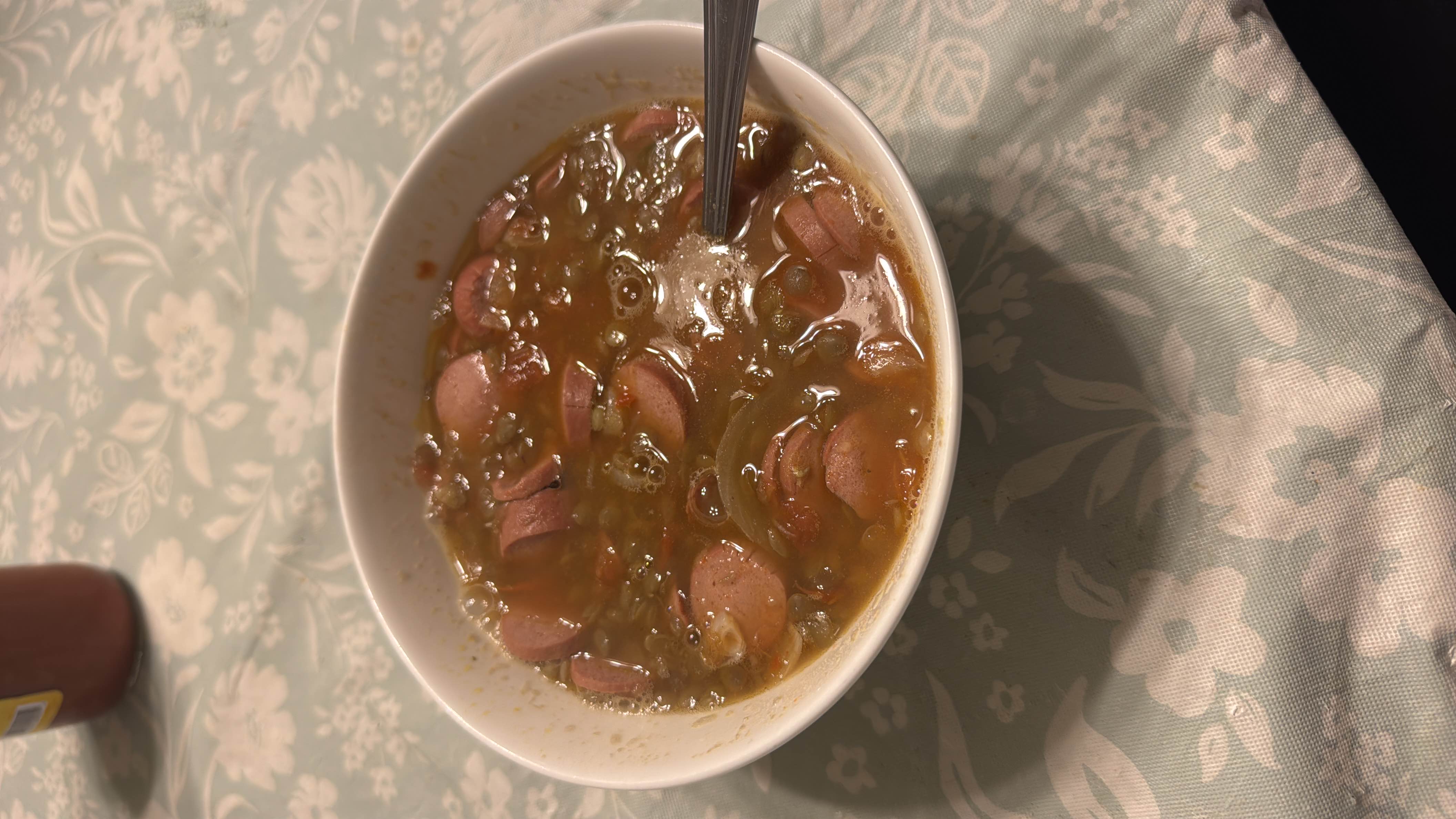 A hearty bowl of lentil soup with sliced sausages, providing a balanced mix of protein, carbs, and fats.