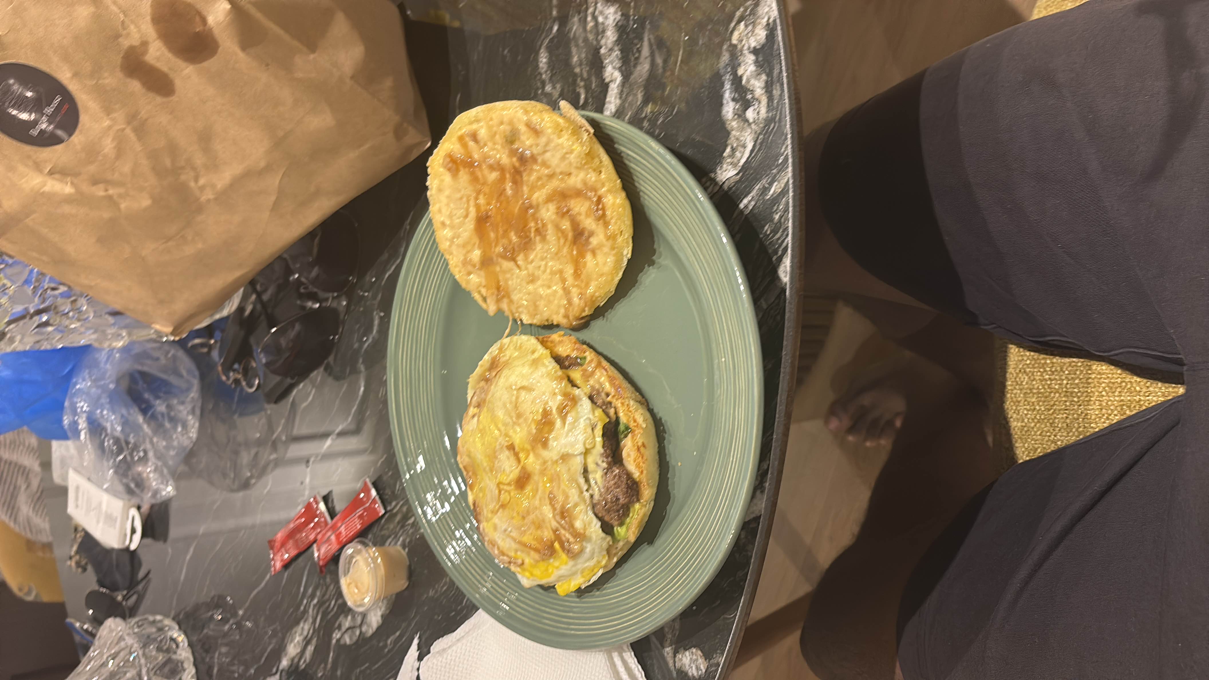 A sandwich consisting of a beef patty, egg, cheese, and bread, likely served with condiments.