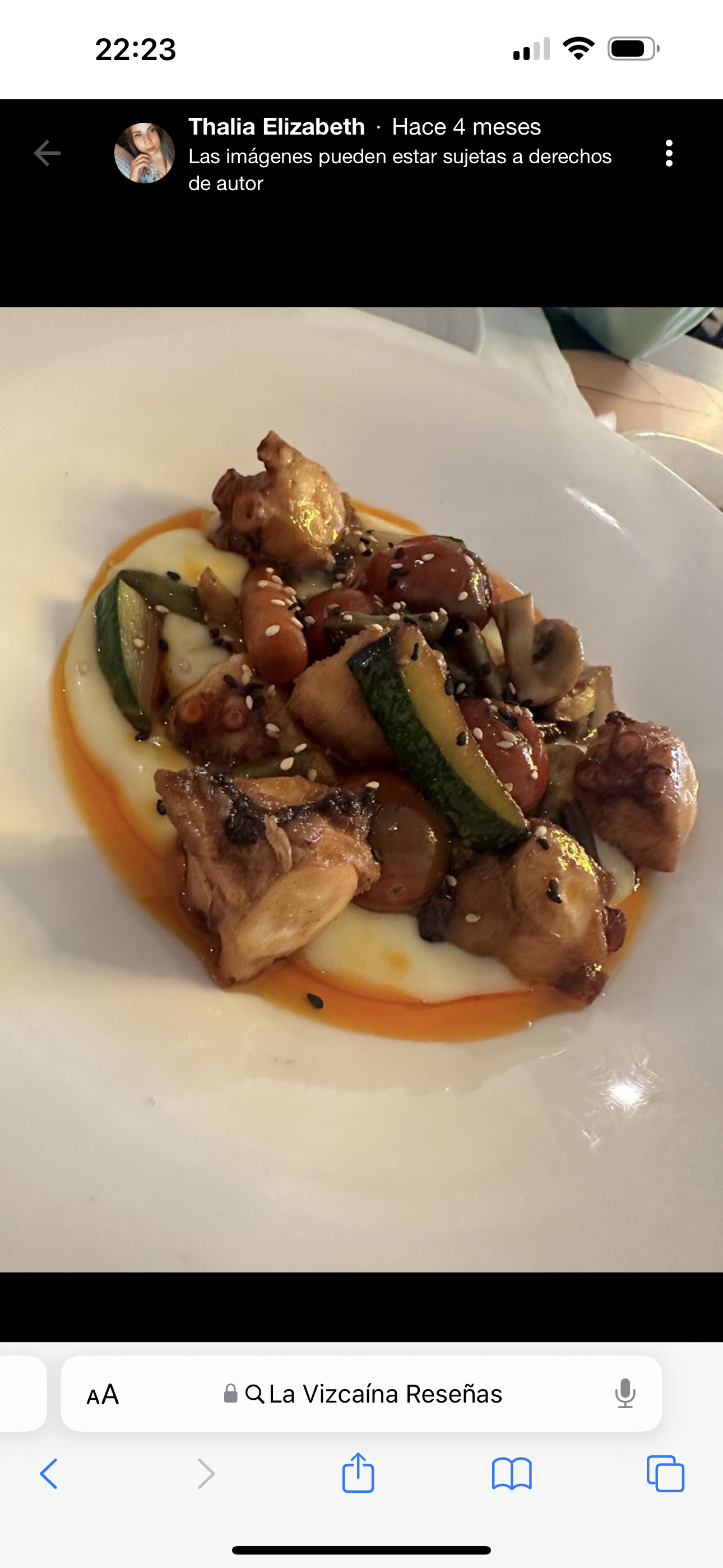 A dish featuring octopus, zucchini, cherry tomatoes, mashed potatoes, and sesame seeds, drizzled with paprika oil.