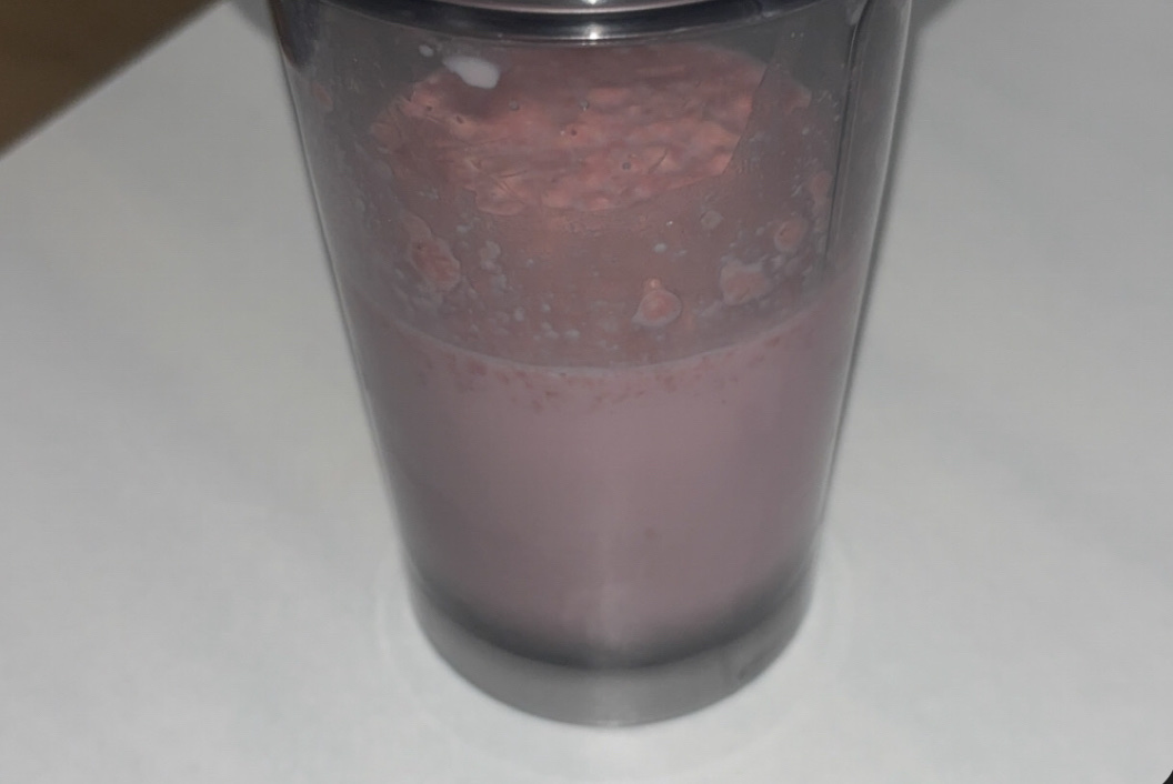 A strawberry milkshake with a creamy texture, providing a balance of protein, carbs, and fats.