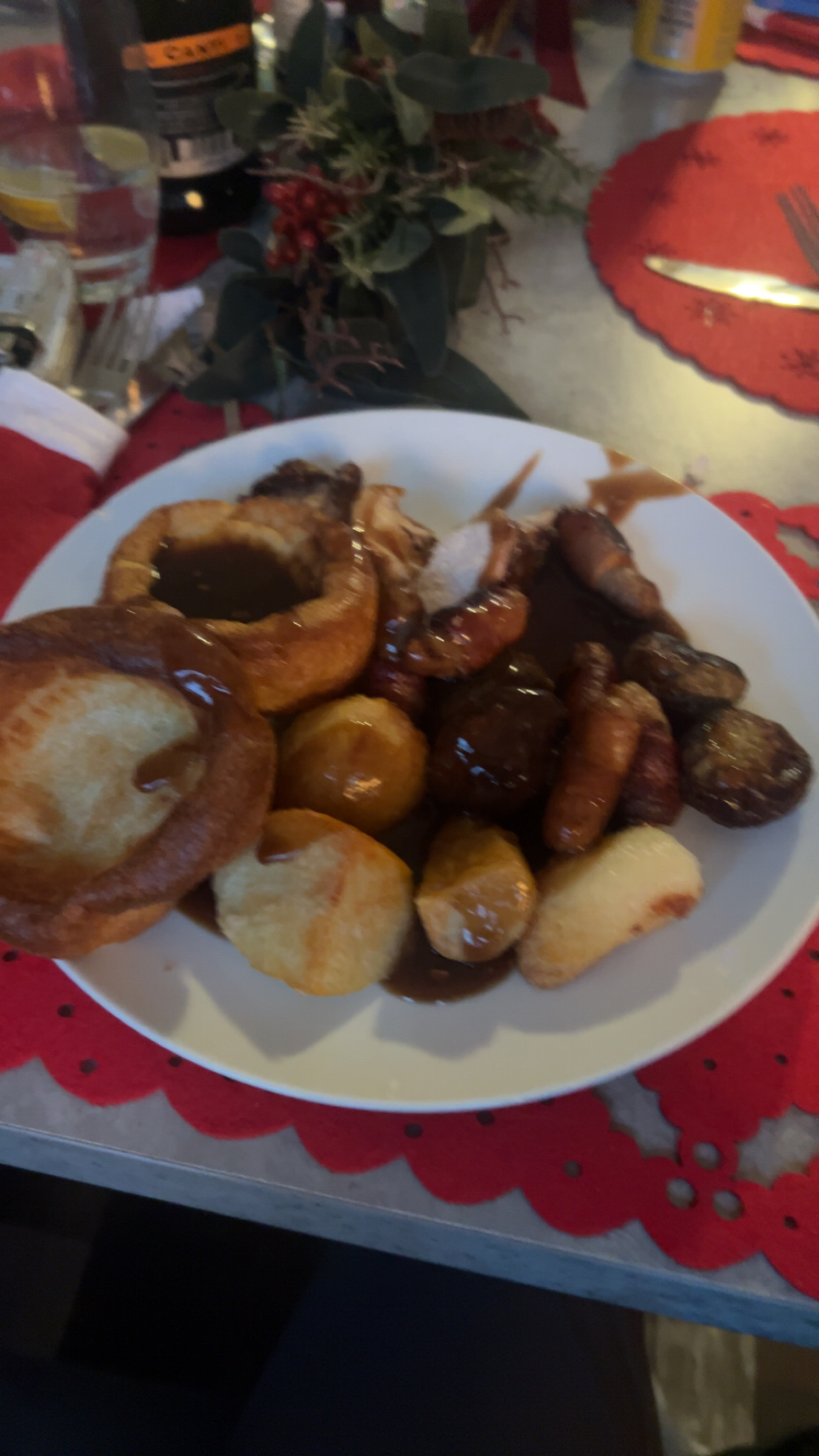A traditional roast dinner featuring roast potatoes, Yorkshire pudding, gravy, roast chicken, and pigs in blankets.