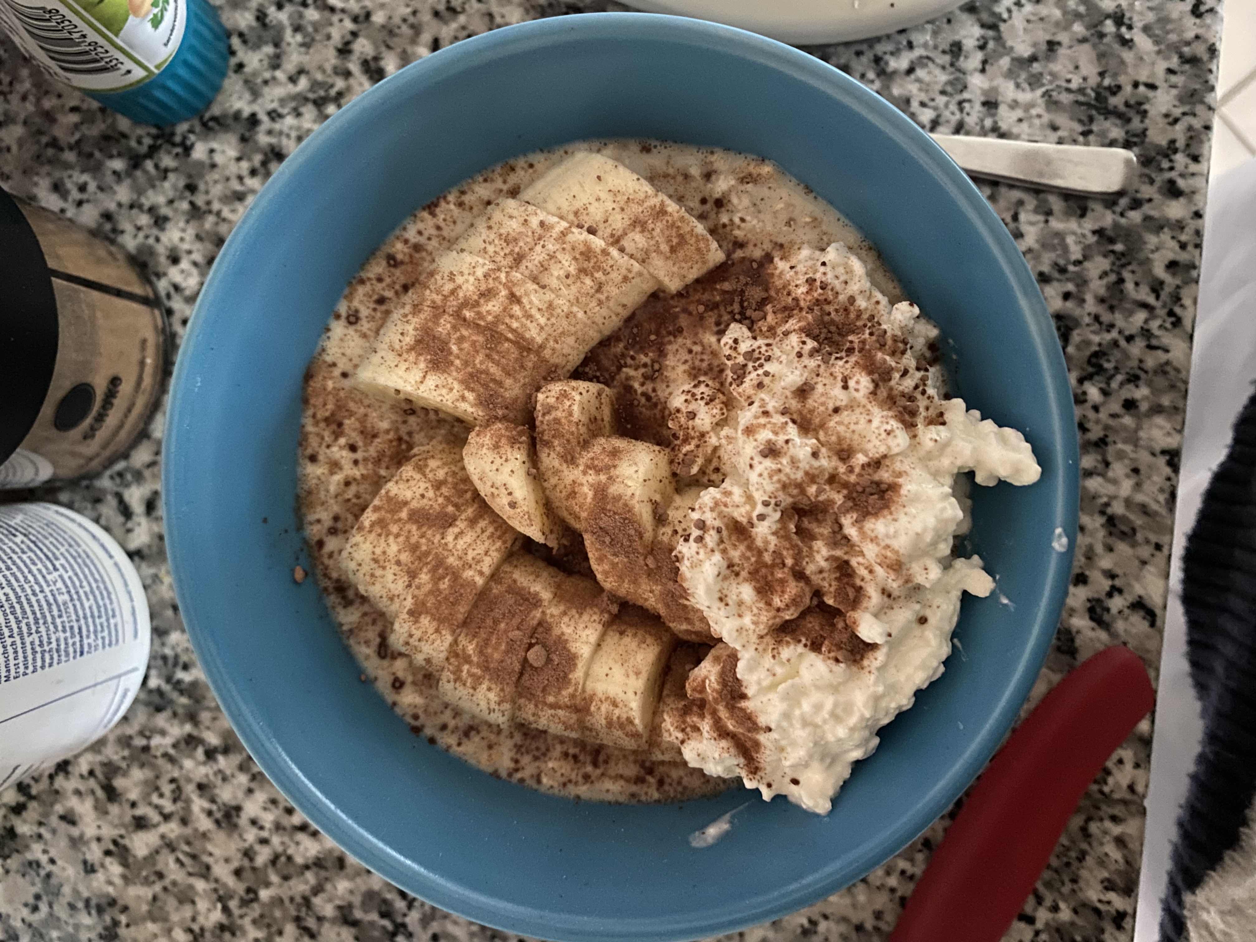 A bowl of oatmeal topped with sliced banana, cottage cheese, and a sprinkle of cinnamon, providing a balanced mix of protein, carbs, and fats.
