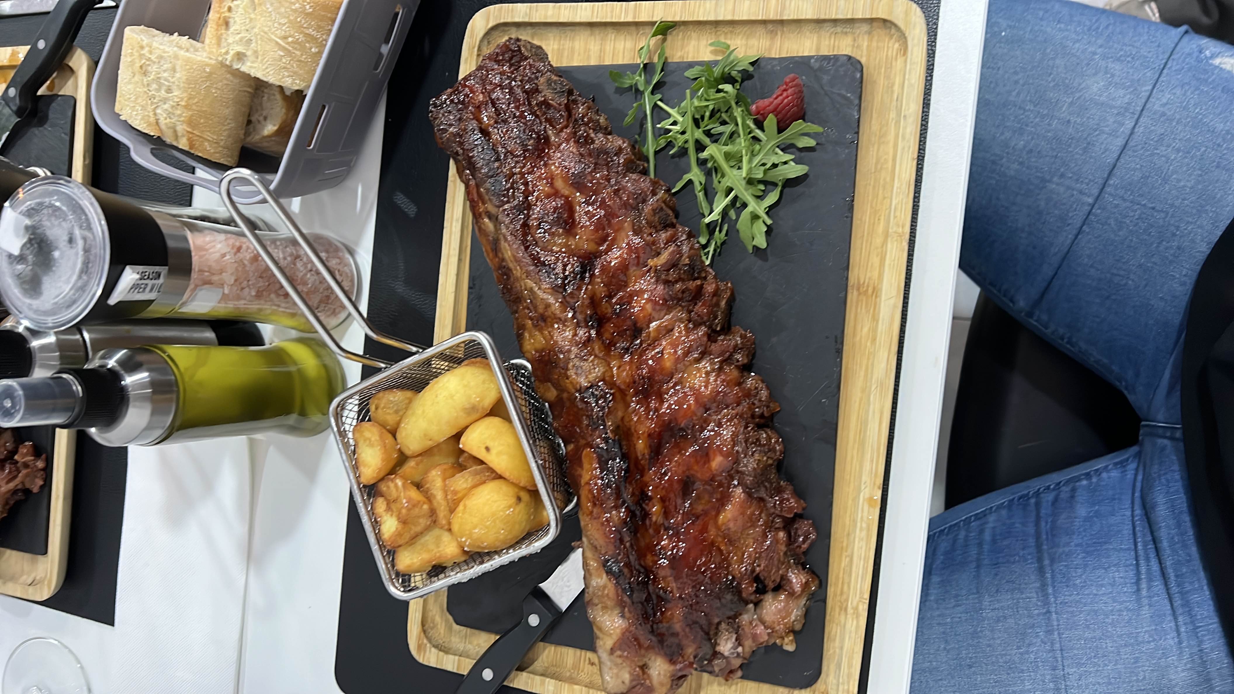 A hearty meal featuring glazed pork ribs, roasted potatoes, arugula, and a raspberry garnish.