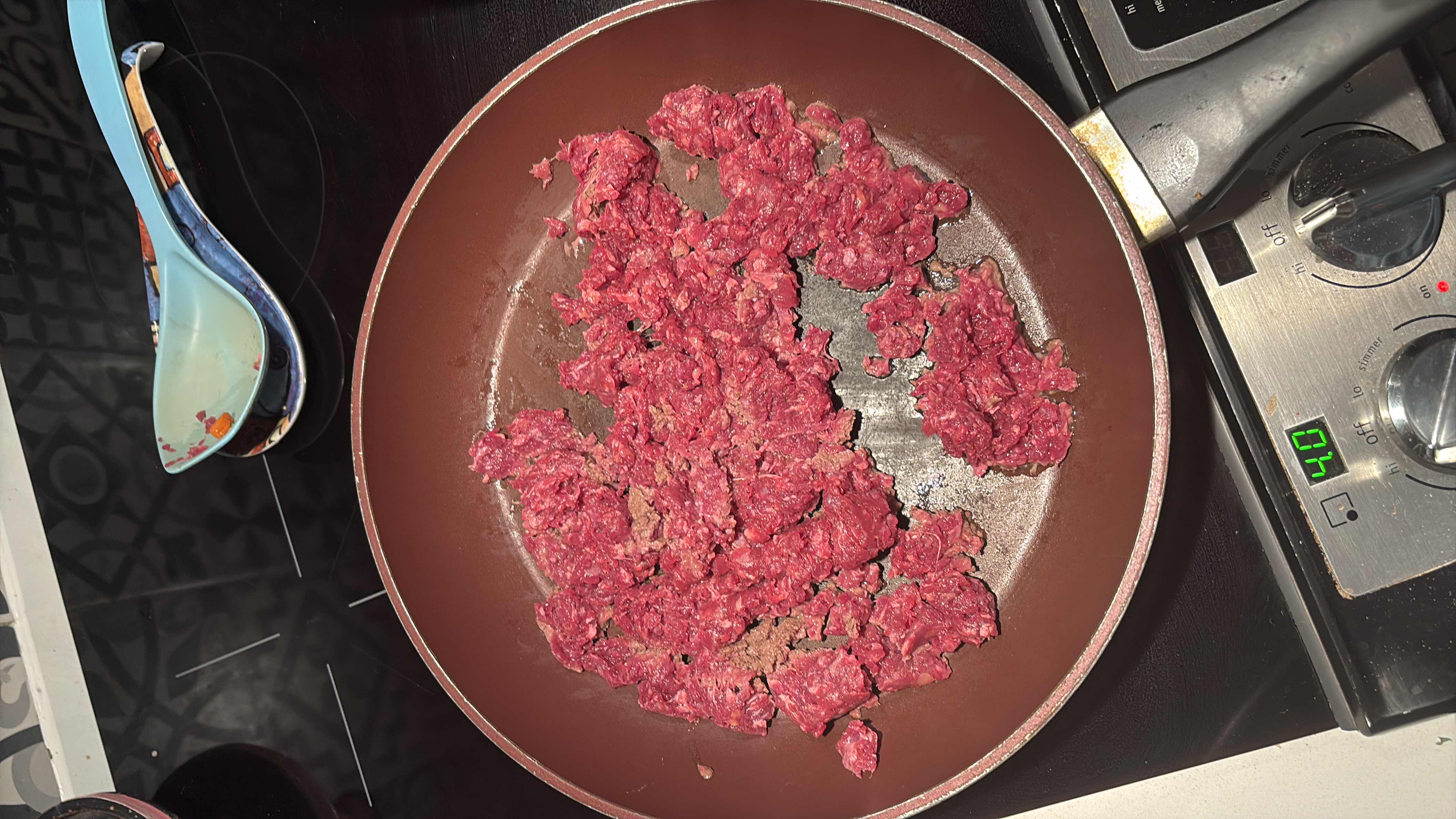 The image shows ground beef being cooked in a pan, which is high in protein and fats with no carbohydrates.