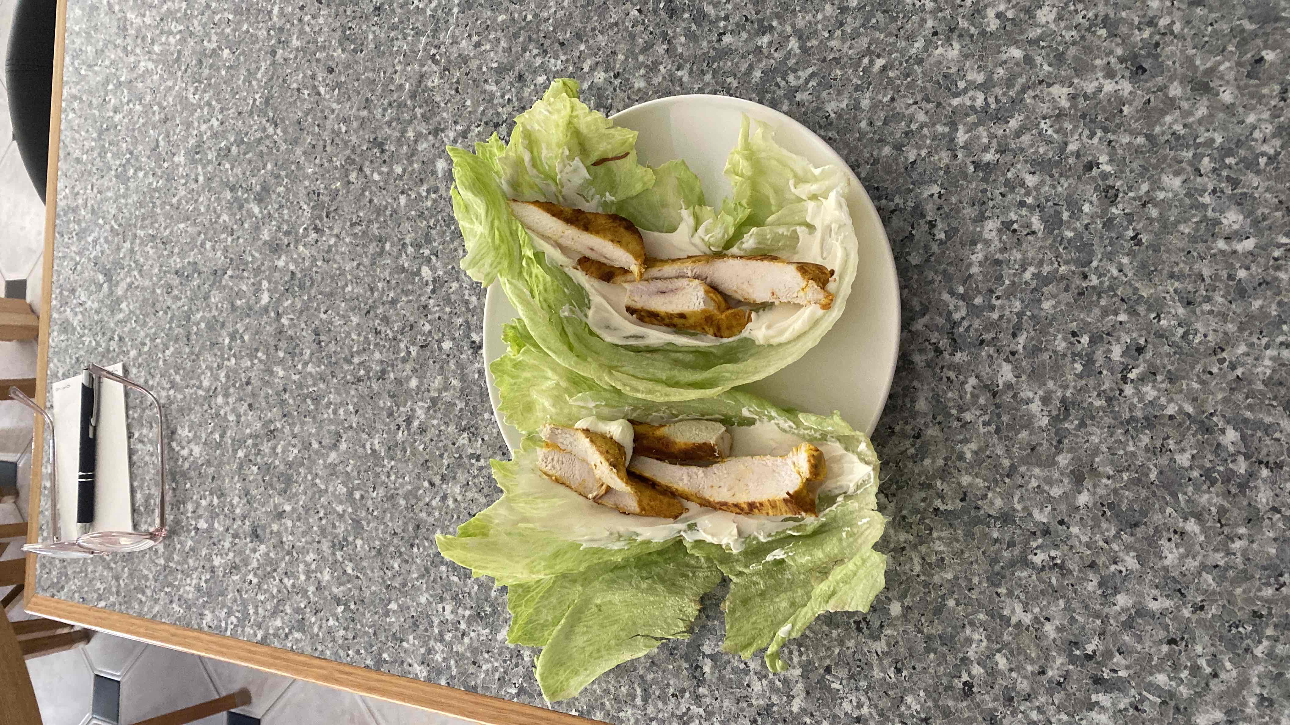 A low-carb meal of grilled chicken breast wrapped in lettuce leaves with a light cream cheese spread.