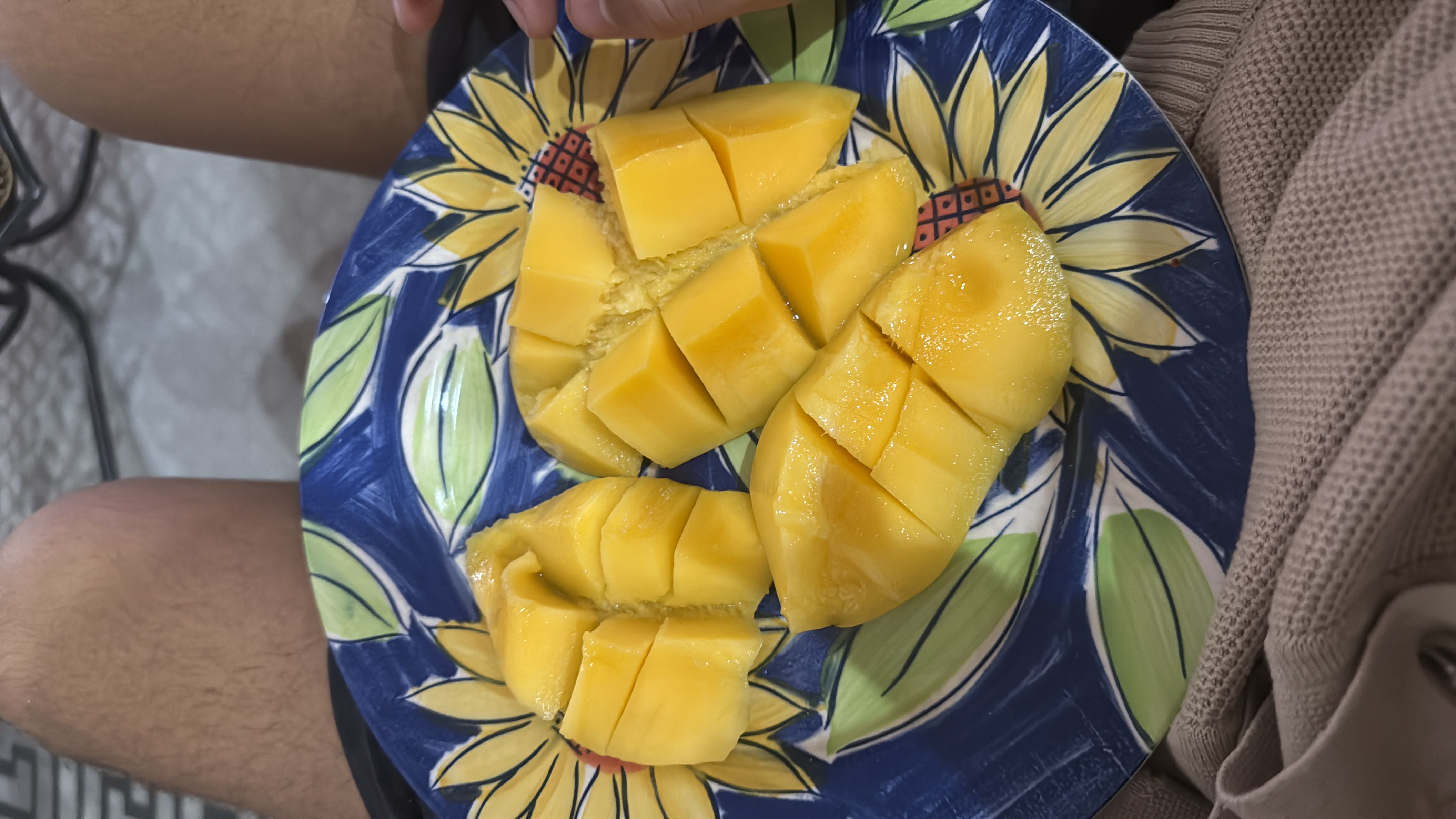 The image shows a plate of sliced mango, a tropical fruit rich in carbohydrates and low in fats and protein.