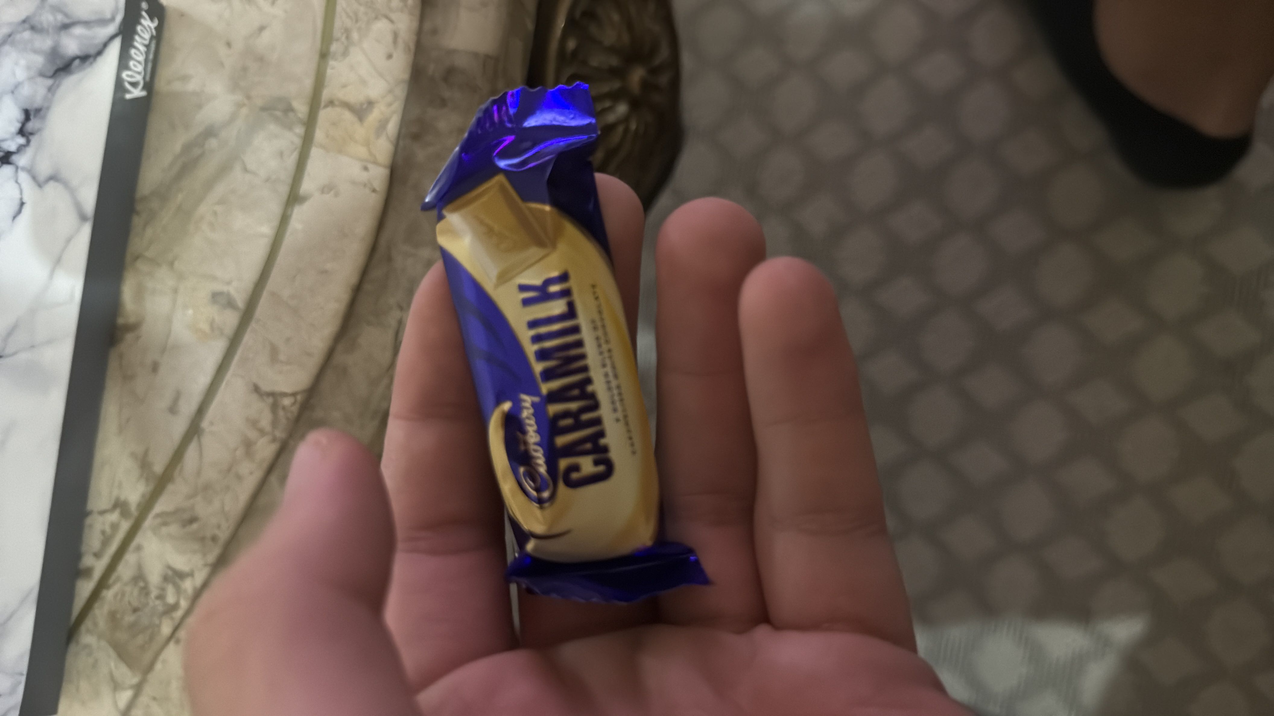 A small piece of Cadbury Caramilk, a caramelized white chocolate treat, with moderate calories and low protein content.