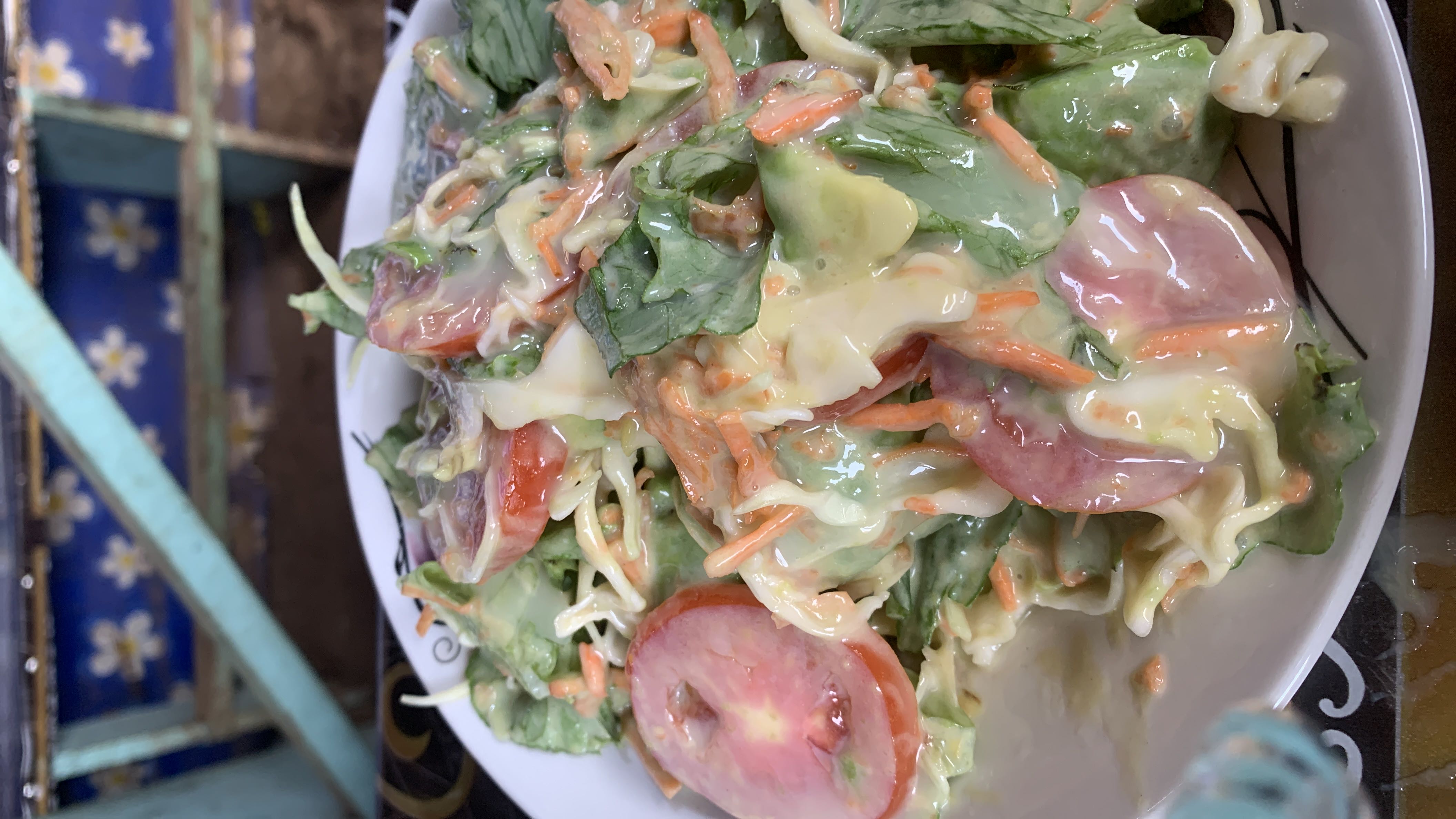 A fresh salad with lettuce, tomato, carrot, and mayonnaise dressing, providing a balanced mix of vegetables and fats.