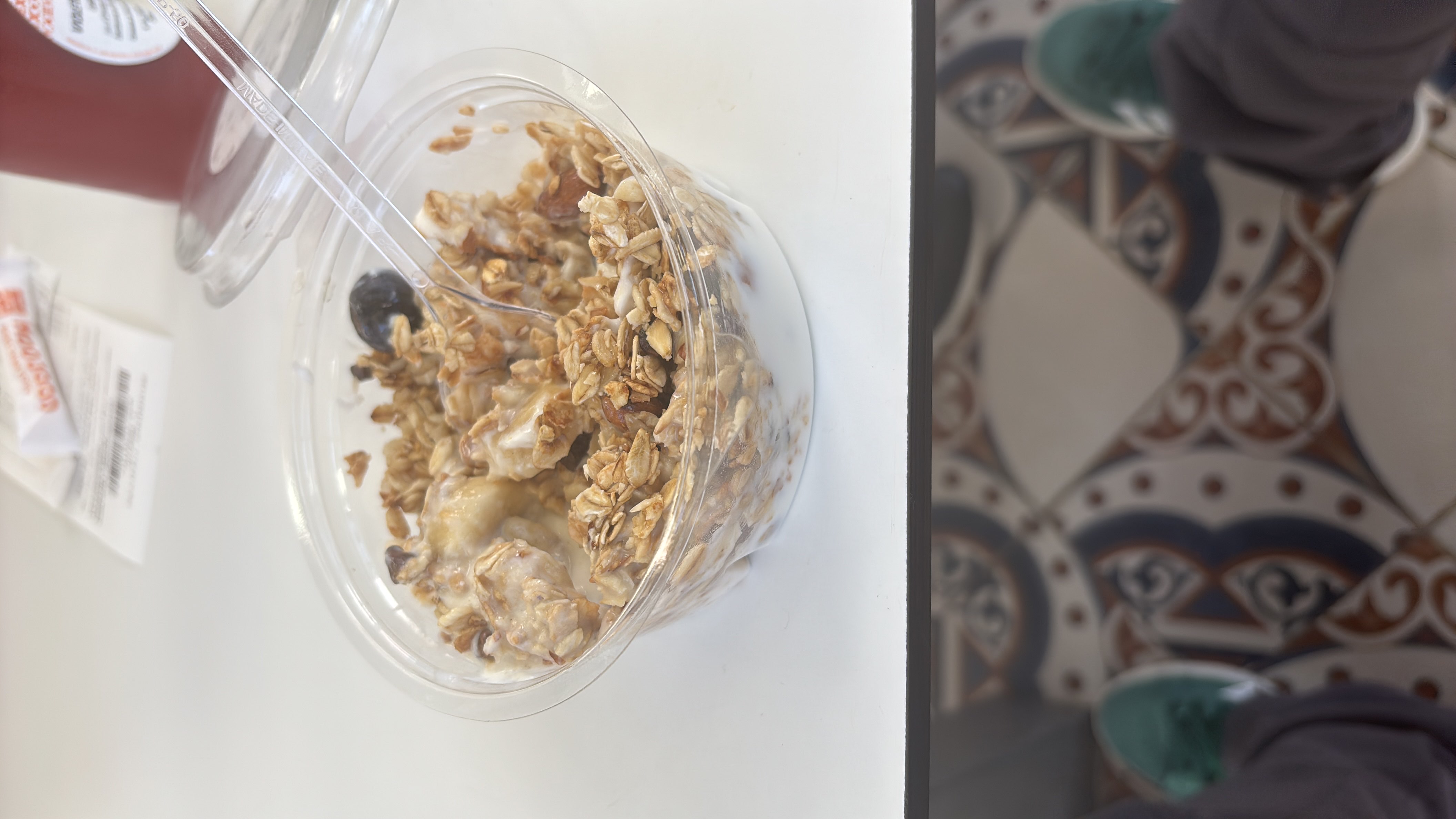 A bowl of yogurt topped with granola, banana slices, and a blueberry, providing a balanced mix of protein, carbs, and fats.