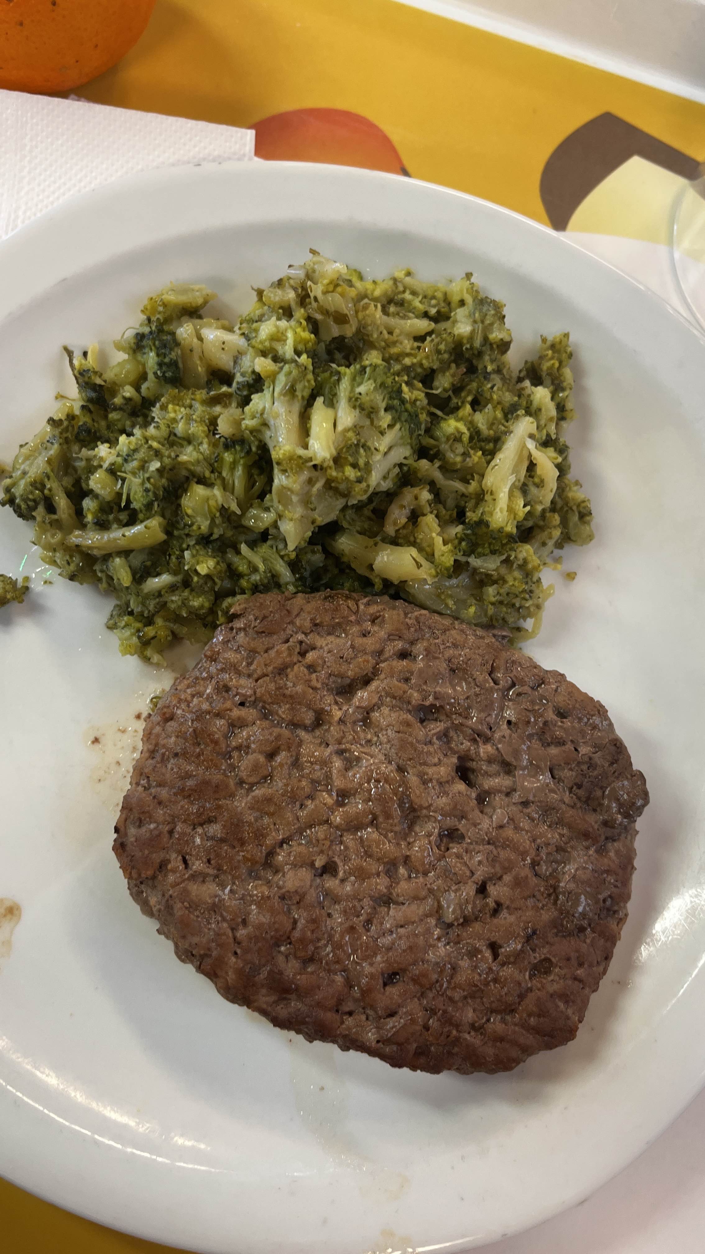 A plate containing a beef patty and steamed broccoli, providing a balanced meal with high protein and moderate fats.