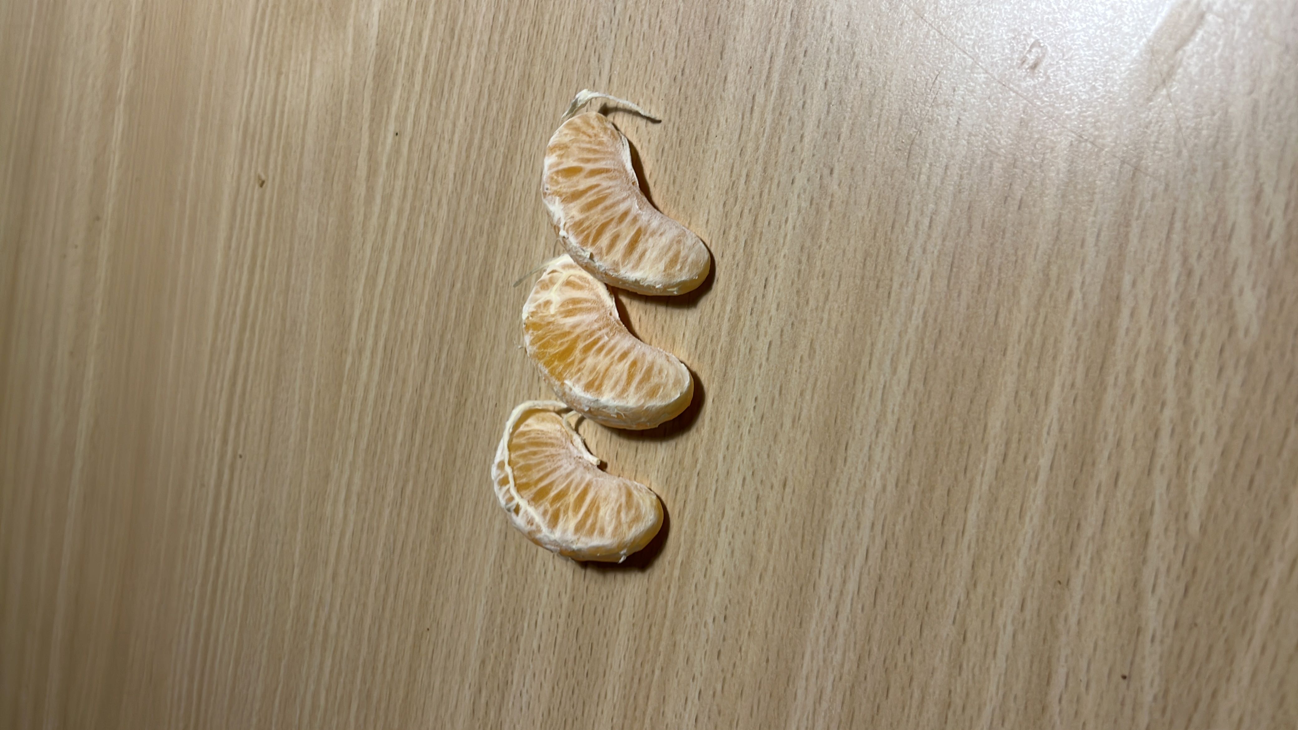 The image shows three mandarin orange slices, which are low in calories and rich in carbohydrates, making them a healthy snack option.