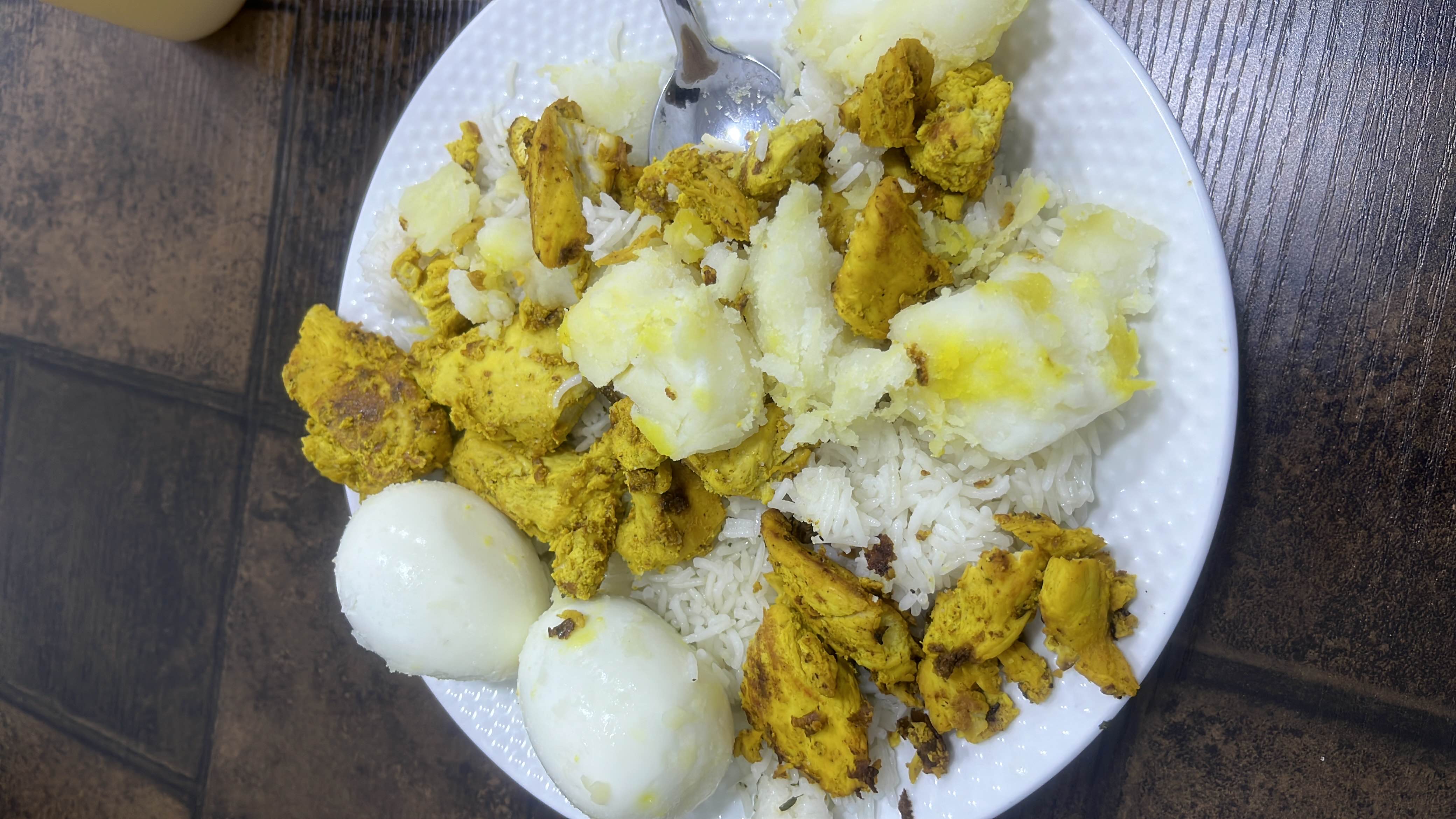 A balanced meal consisting of boiled eggs, grilled chicken, boiled potatoes, and white rice, providing a good mix of protein, carbs, and fats.