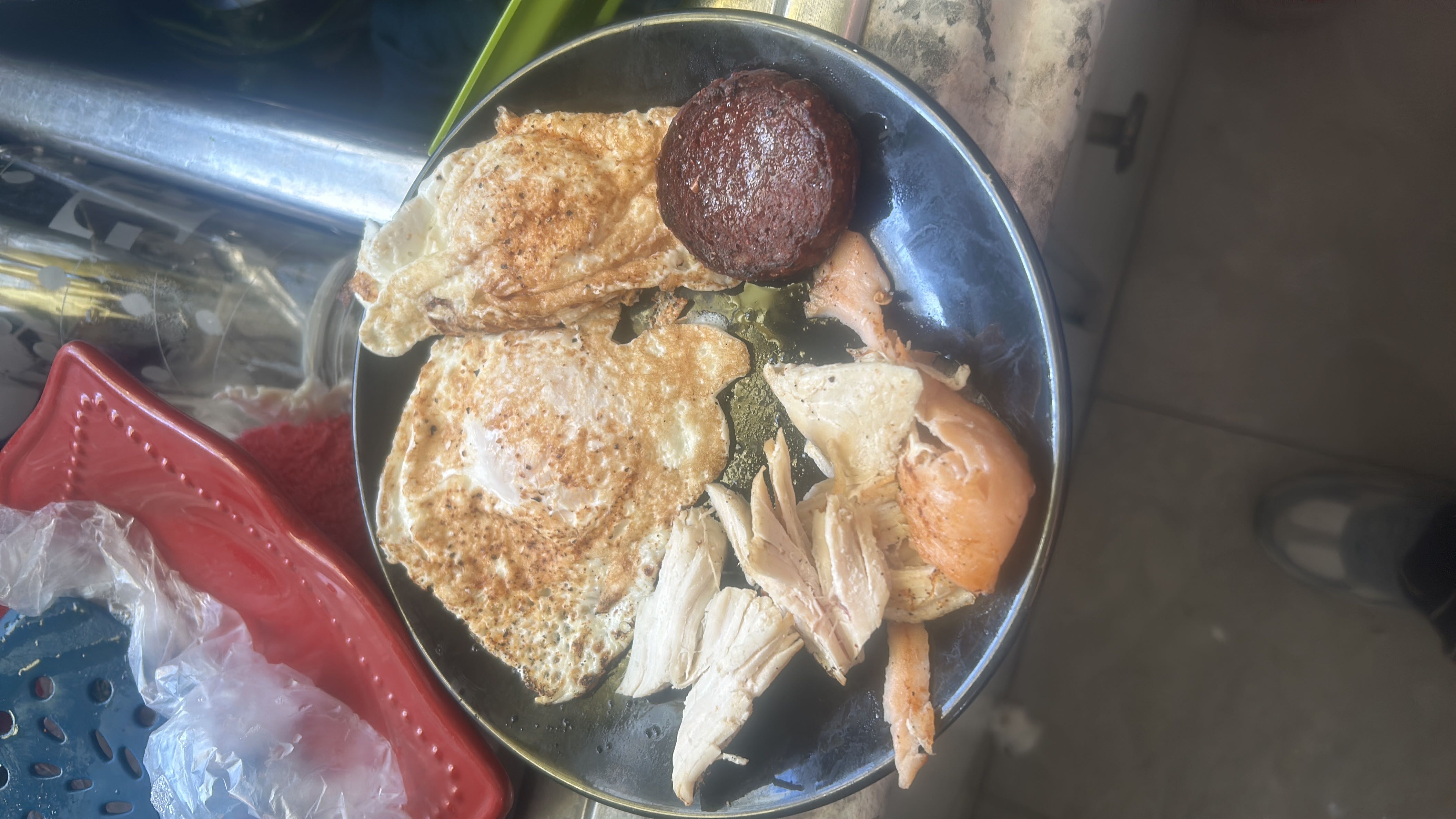 A high-protein meal consisting of fried eggs, chicken pieces, and a sausage patty, with minimal carbohydrates.