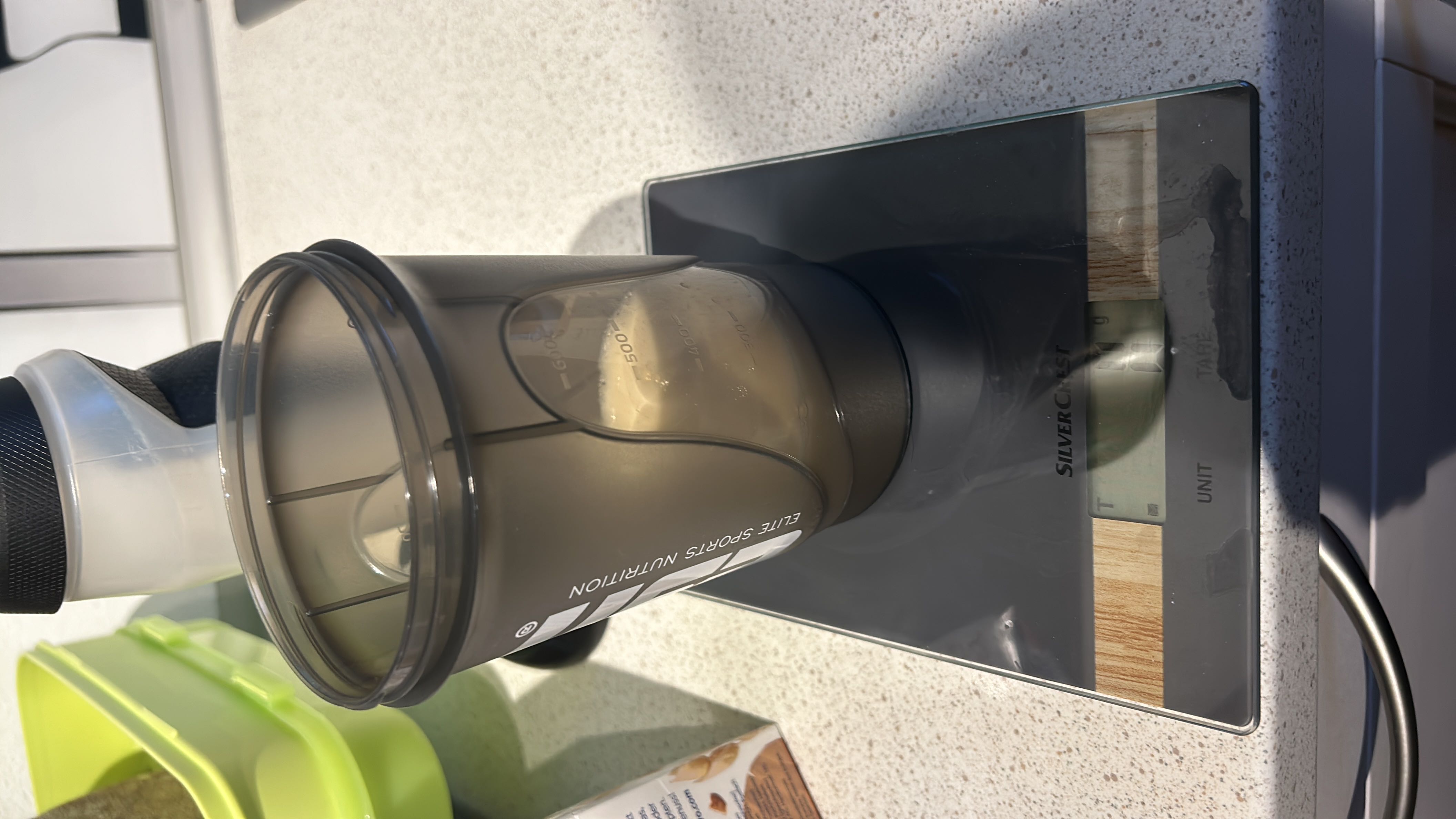 A protein shake mix with milk measured on a kitchen scale, suitable for a healthy diet.