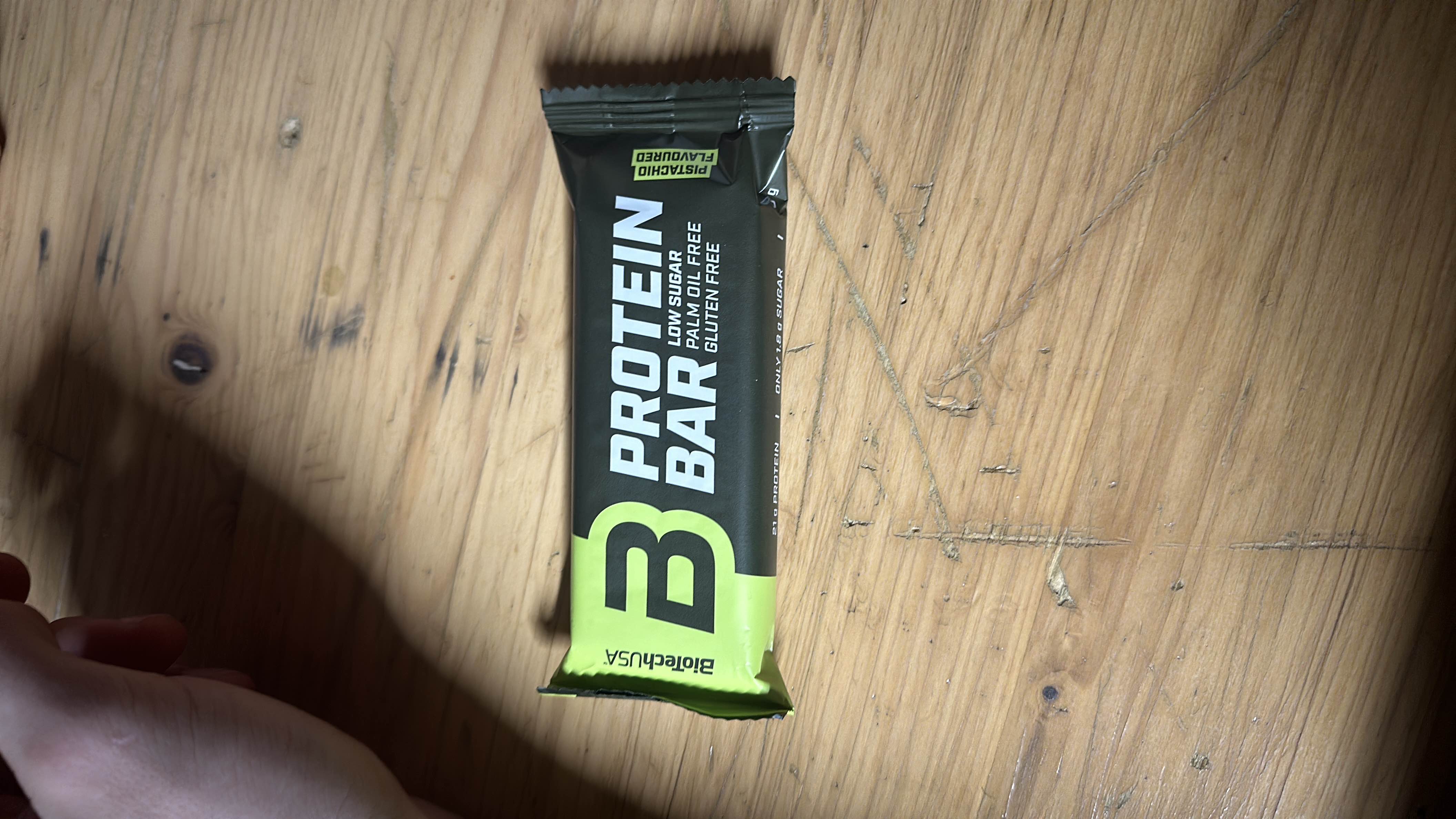 A pistachio-flavored protein bar with 21g of protein, low sugar, and gluten-free, designed for health-conscious individuals.