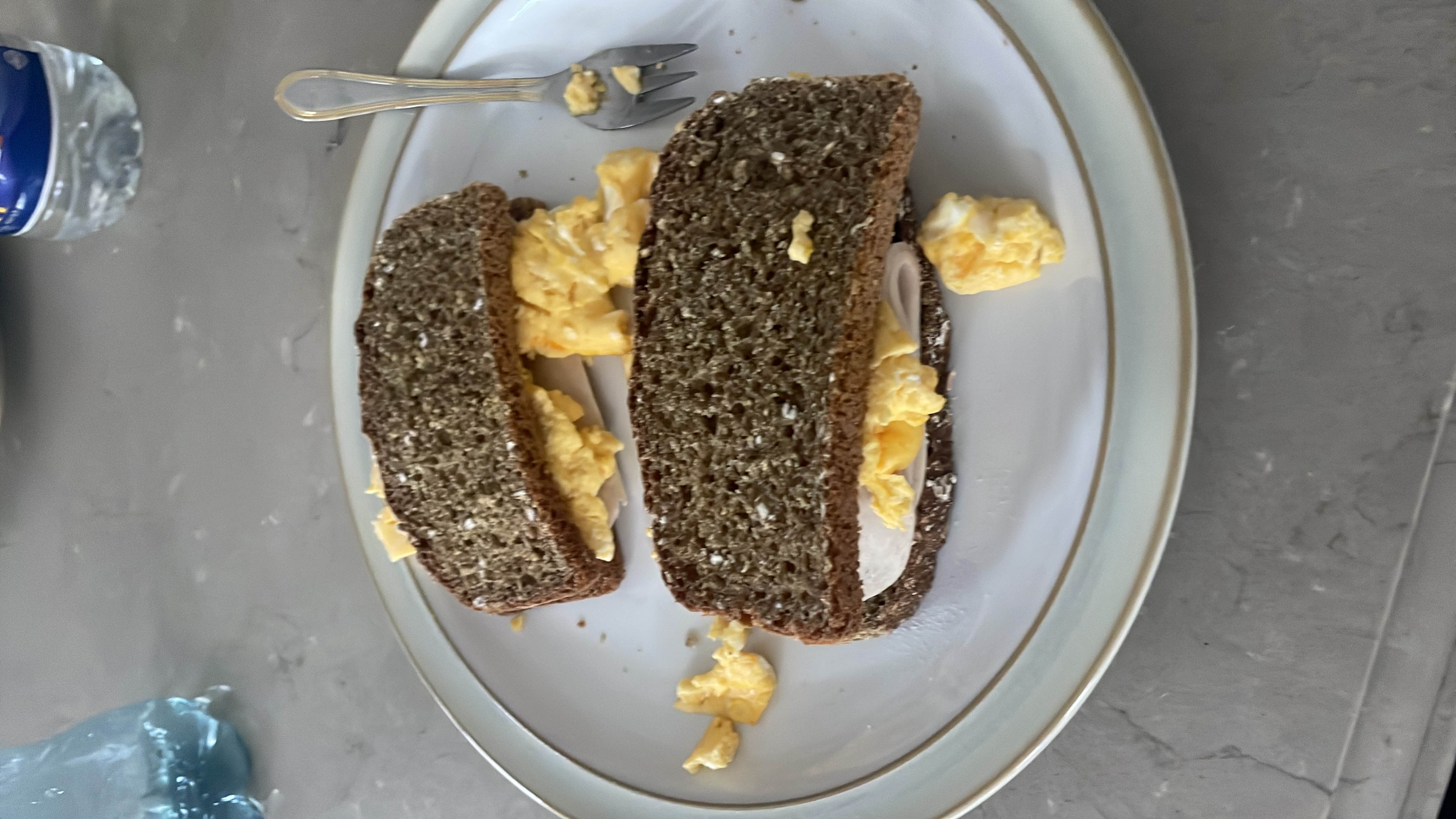 A healthy sandwich made with whole grain bread, scrambled eggs, and turkey slices, providing a balanced mix of protein, carbs, and fats.