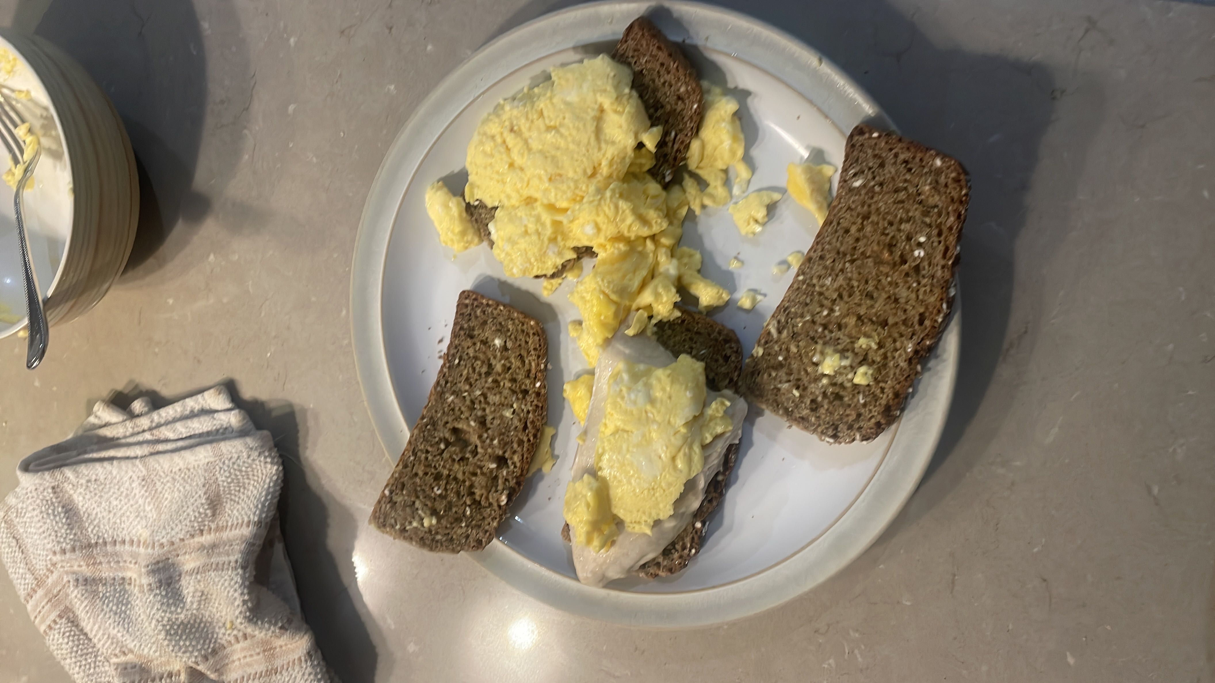 A plate of scrambled eggs served on slices of whole grain bread, providing a balanced mix of protein, carbs, and fats.