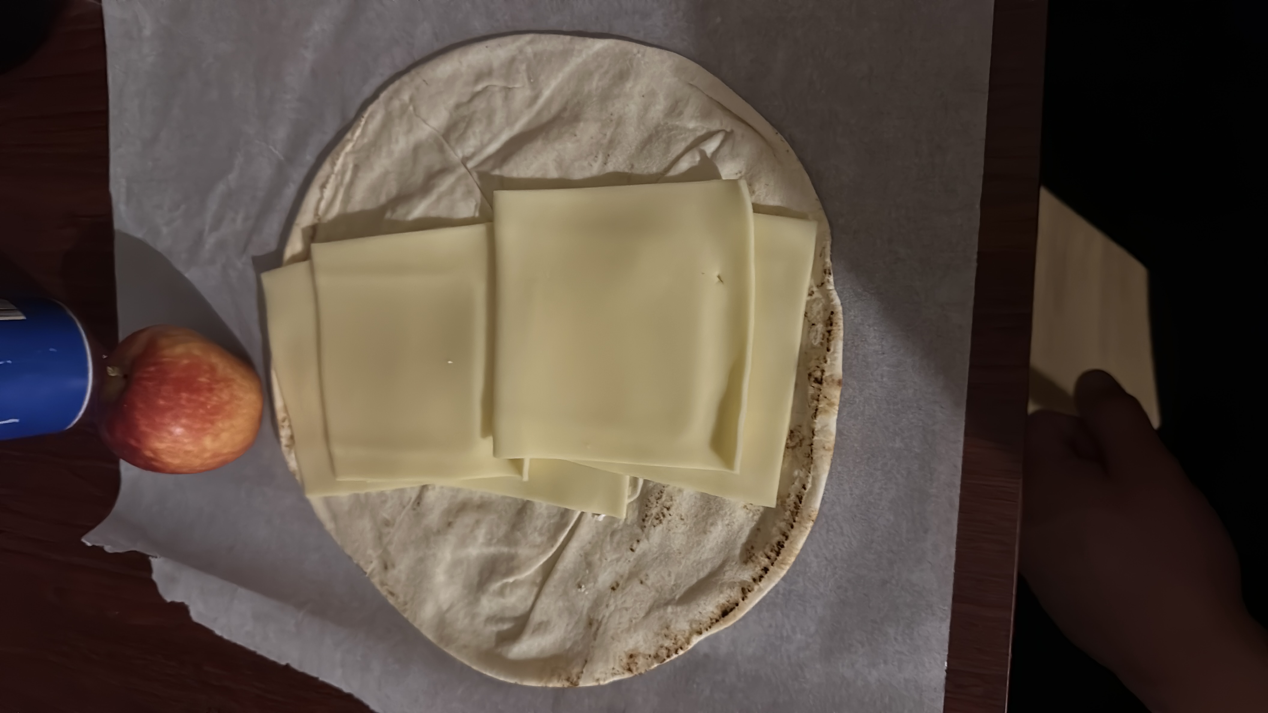 A simple meal consisting of a tortilla with cheese slices and an apple, providing a balance of carbs, protein, and fats.