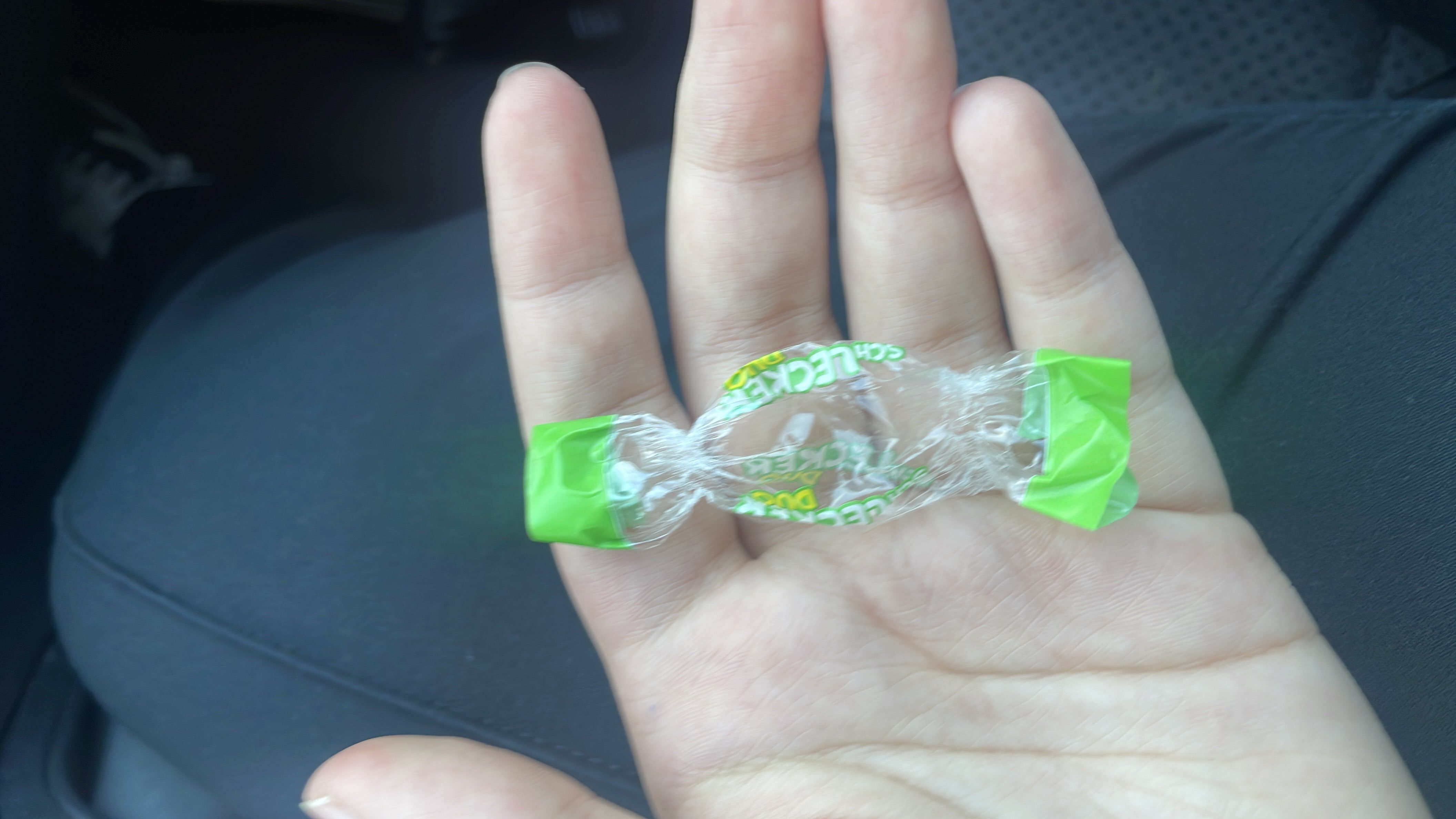 The image shows an empty wrapper of a small candy, likely containing sugar as the primary ingredient.