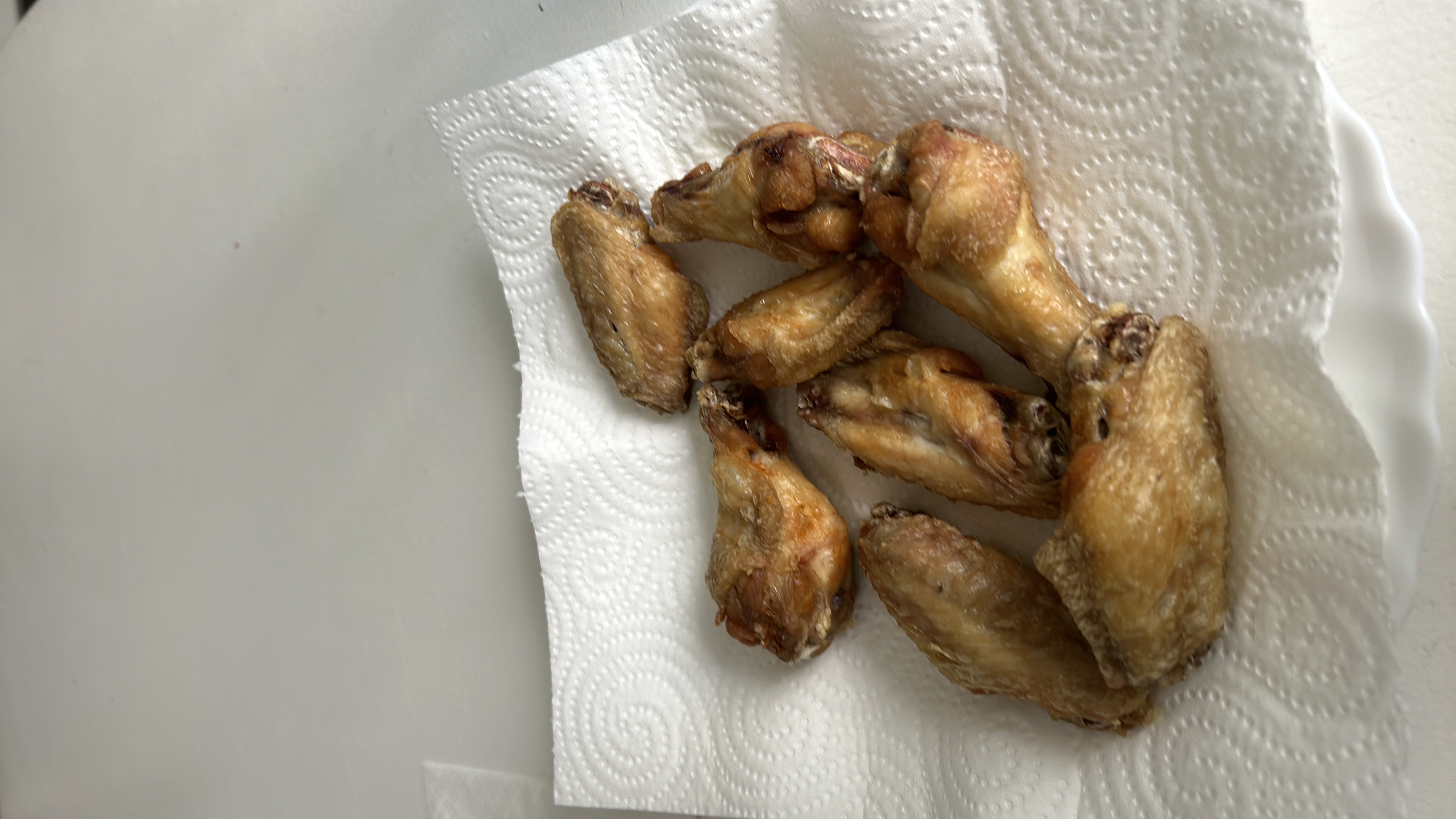 The image shows a plate of cooked chicken wings, which are high in protein and fats with no carbohydrates.