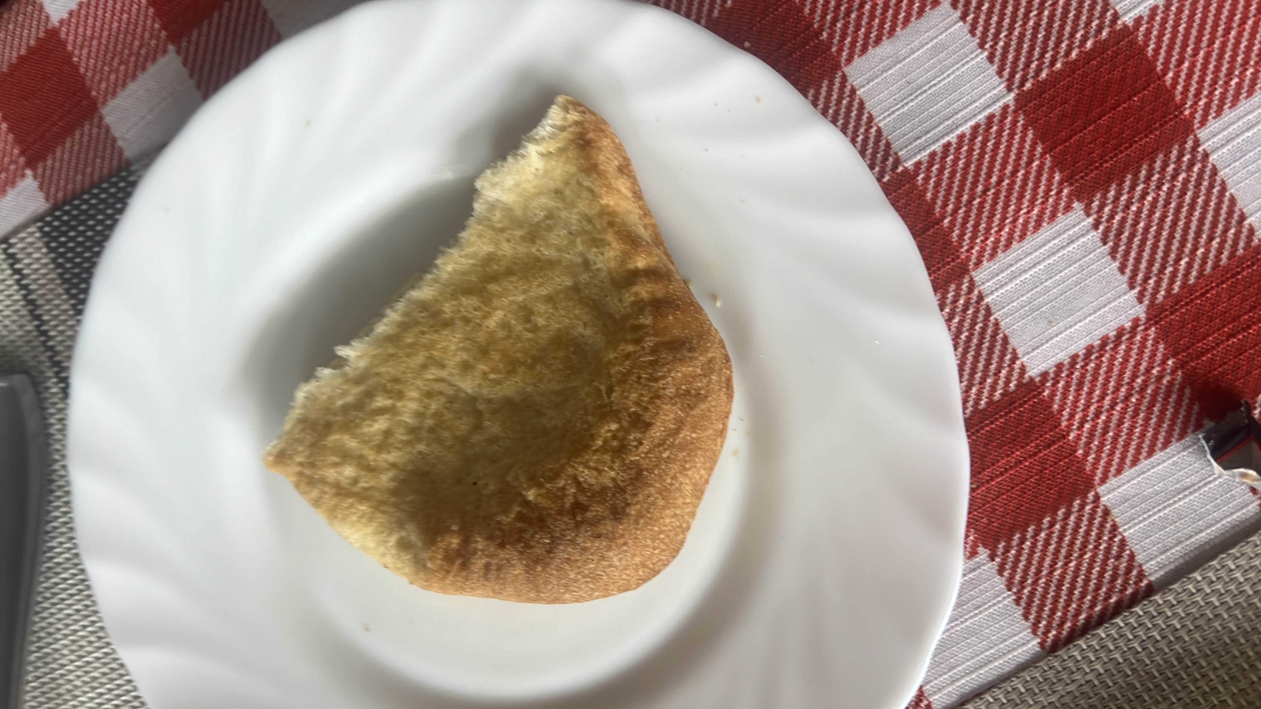 A single slice of bread, lightly toasted, served on a white plate.