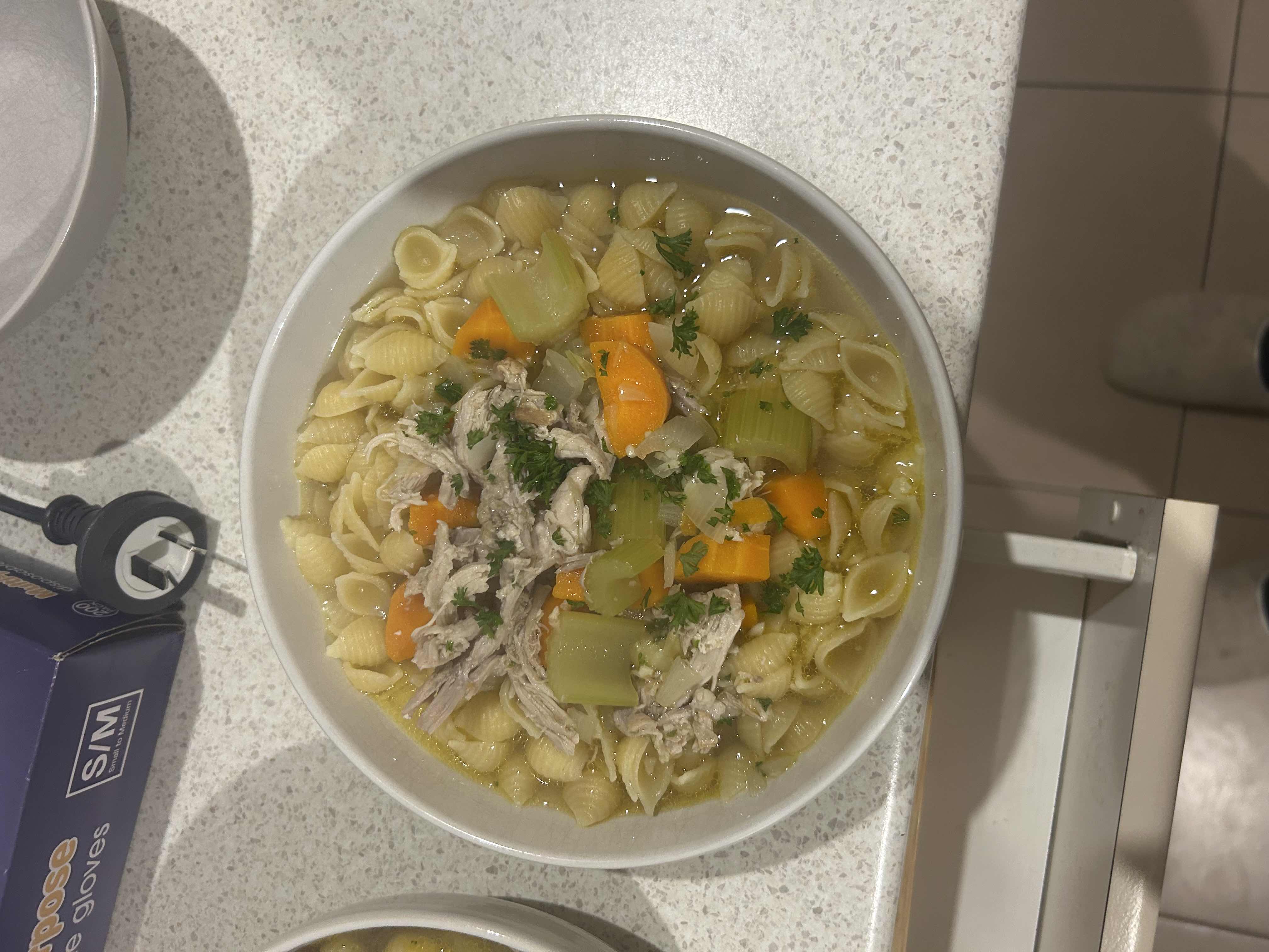 A hearty chicken noodle soup with pasta, carrots, celery, and broth, garnished with parsley.