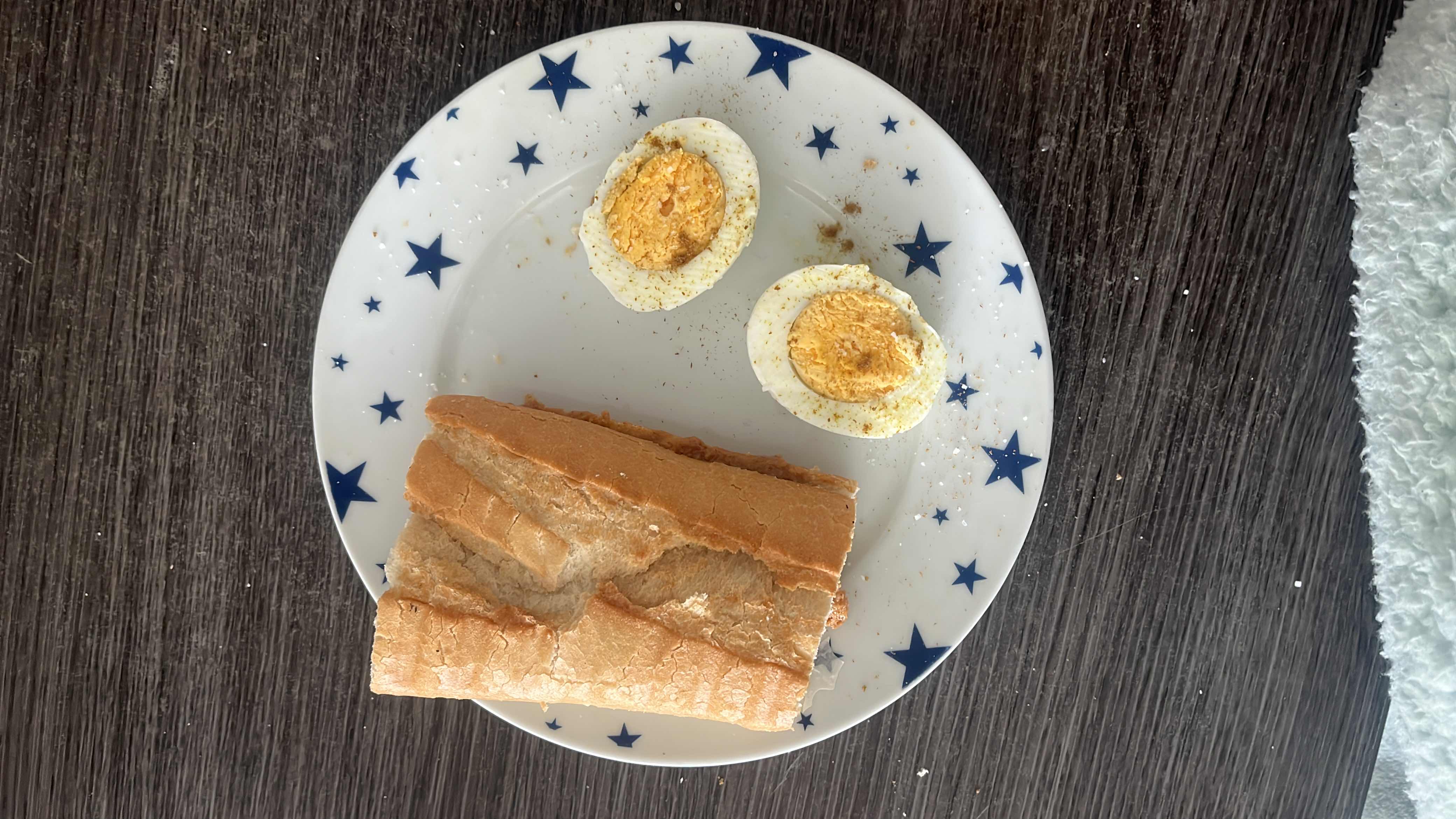 A plate containing a piece of bread and two halves of a boiled egg, providing a balanced mix of carbohydrates, protein, and fats.