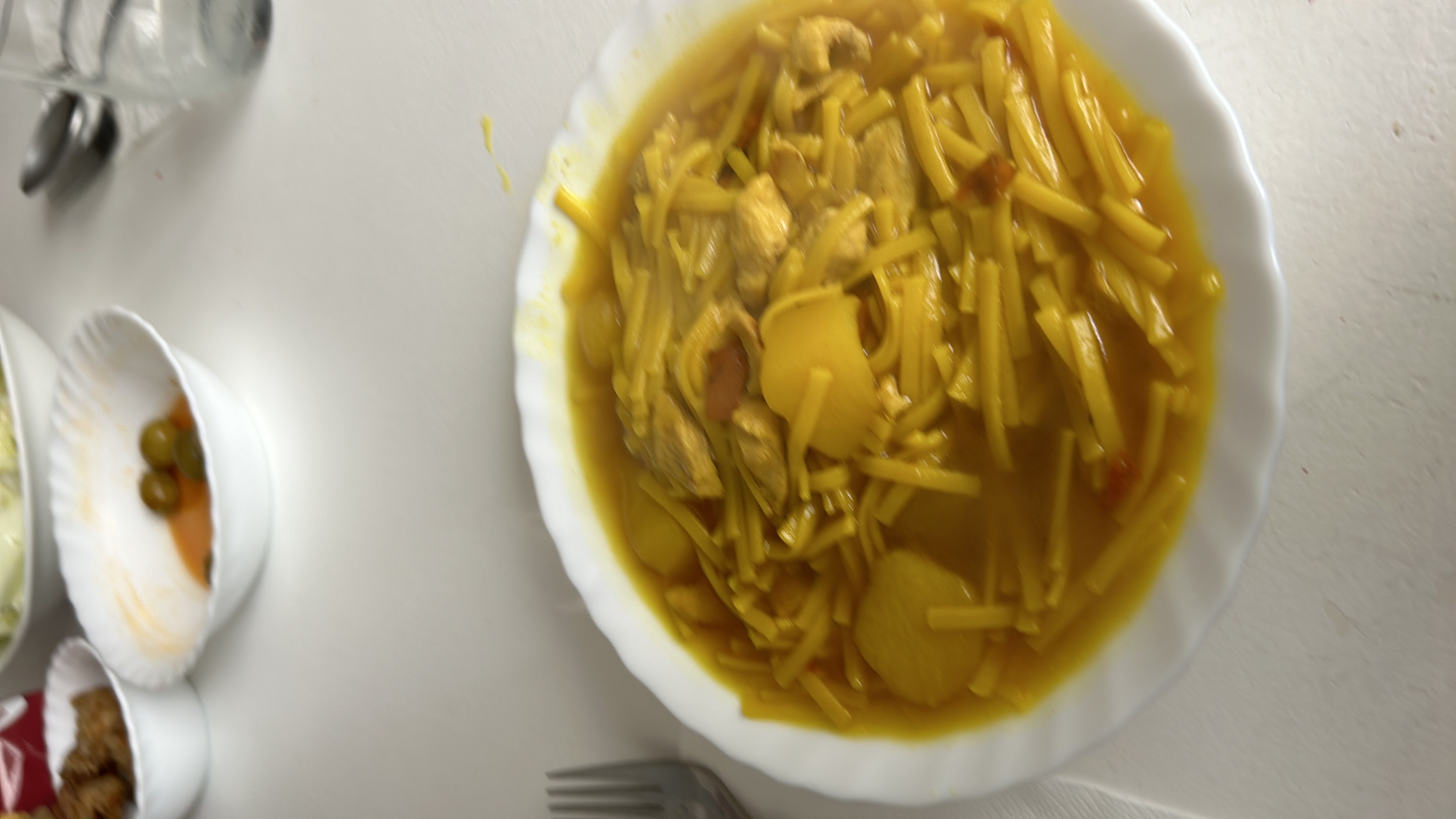 A bowl of noodle soup with chicken and potatoes, providing a balanced mix of protein, carbs, and fats.