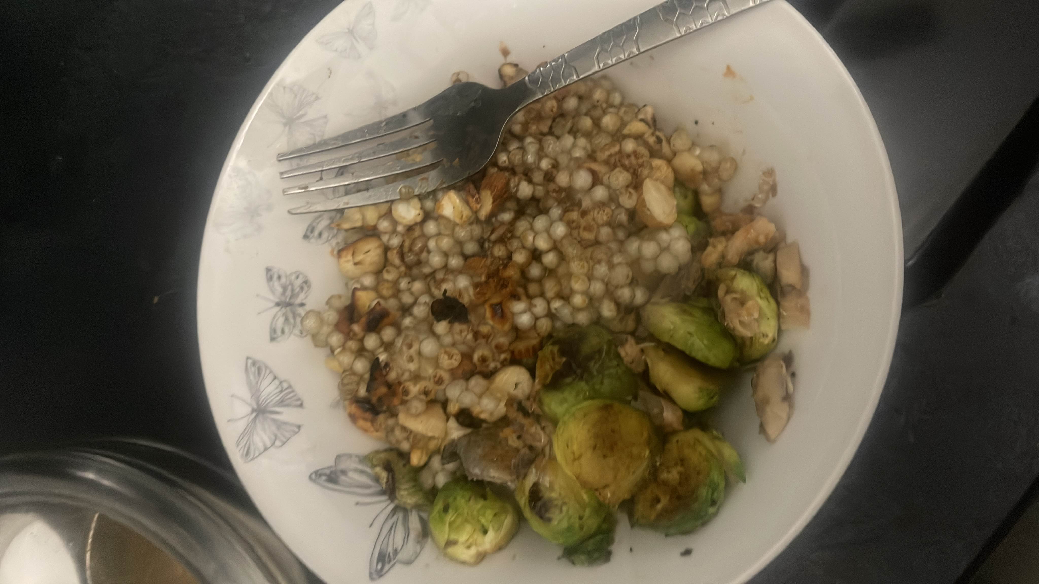 A healthy dish consisting of roasted Brussels sprouts, pearl couscous, and nuts, providing a balanced mix of protein, carbs, and fats.
