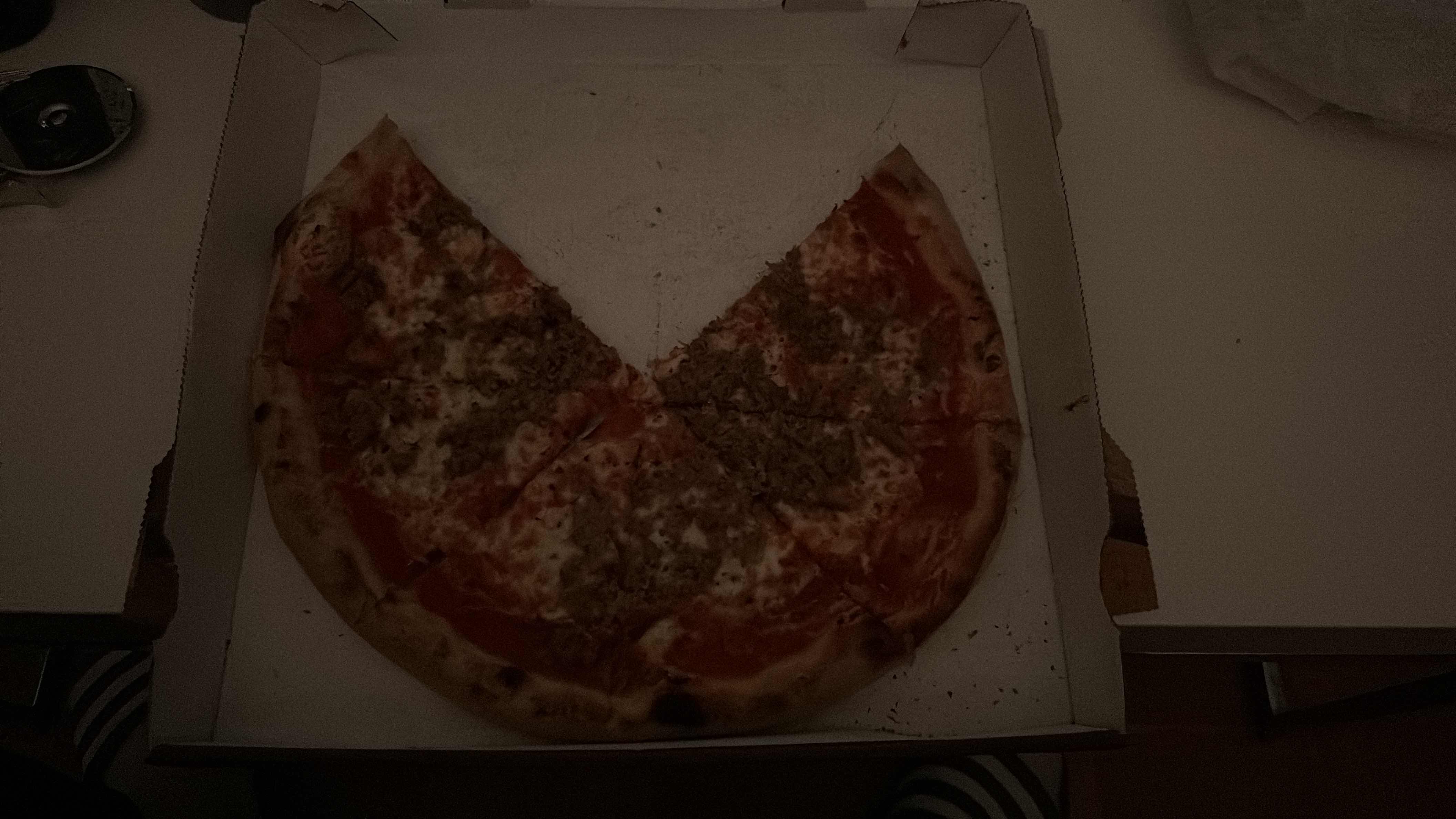 A pizza with cheese, tomato sauce, ground meat, and a thin crust, partially eaten.