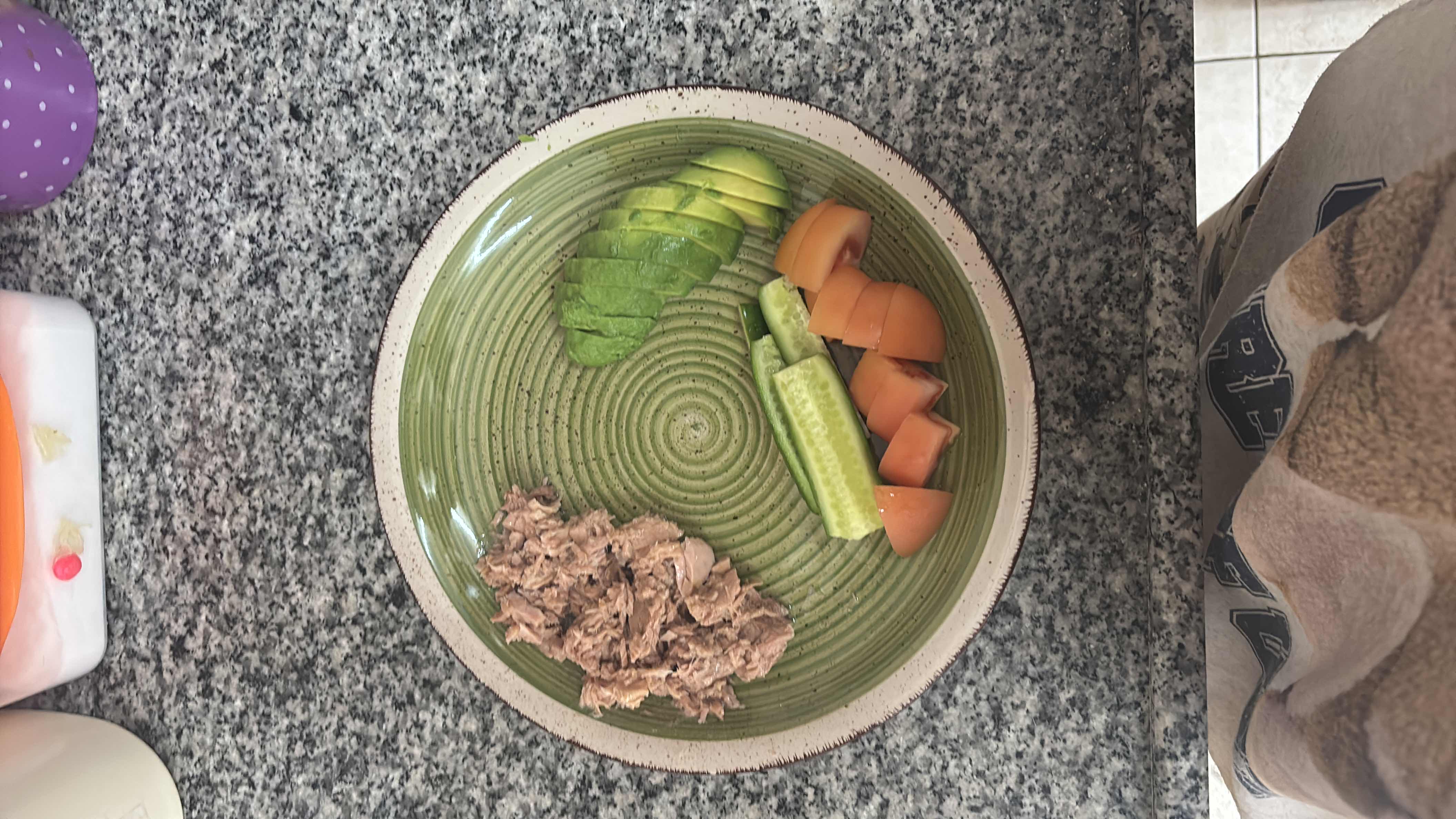 A healthy plate consisting of tuna, avocado slices, cucumber, and tomato, providing a balanced mix of protein, healthy fats, and low carbs.