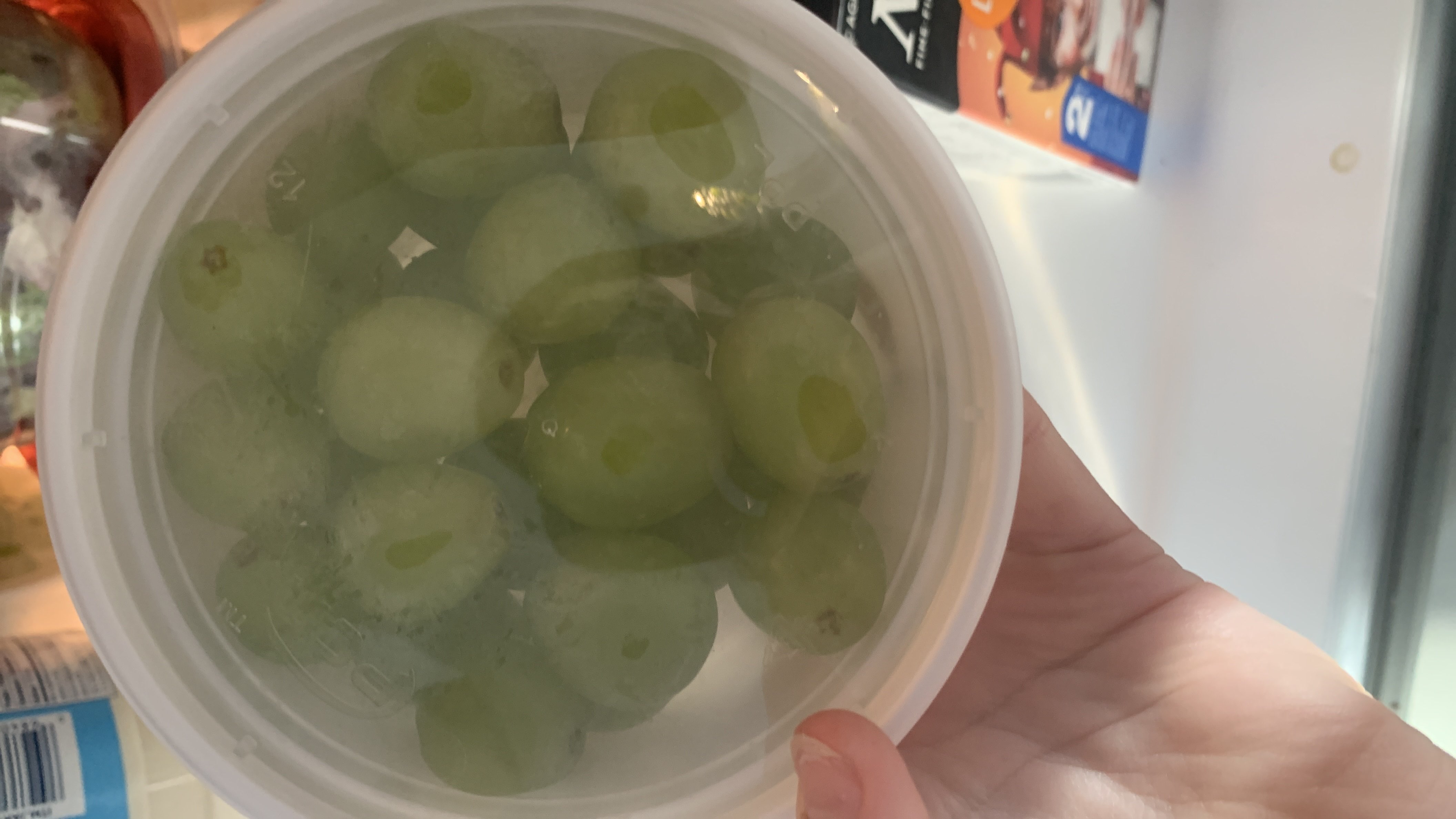 A container of green grapes, a low-calorie fruit rich in carbohydrates and minimal protein and fats.
