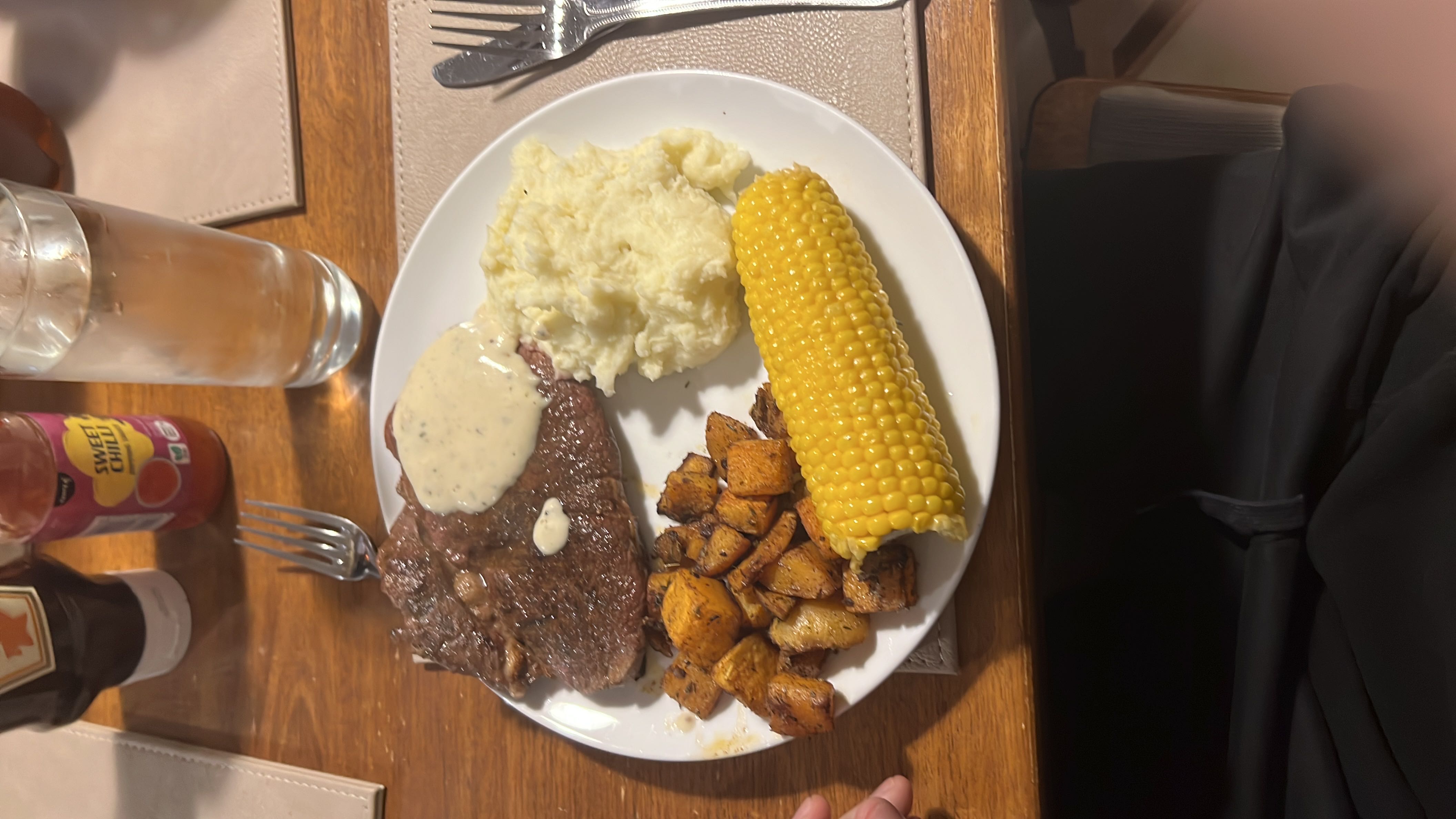 A balanced meal consisting of steak, mashed potatoes, roasted sweet potatoes, corn on the cob, and cream sauce.
