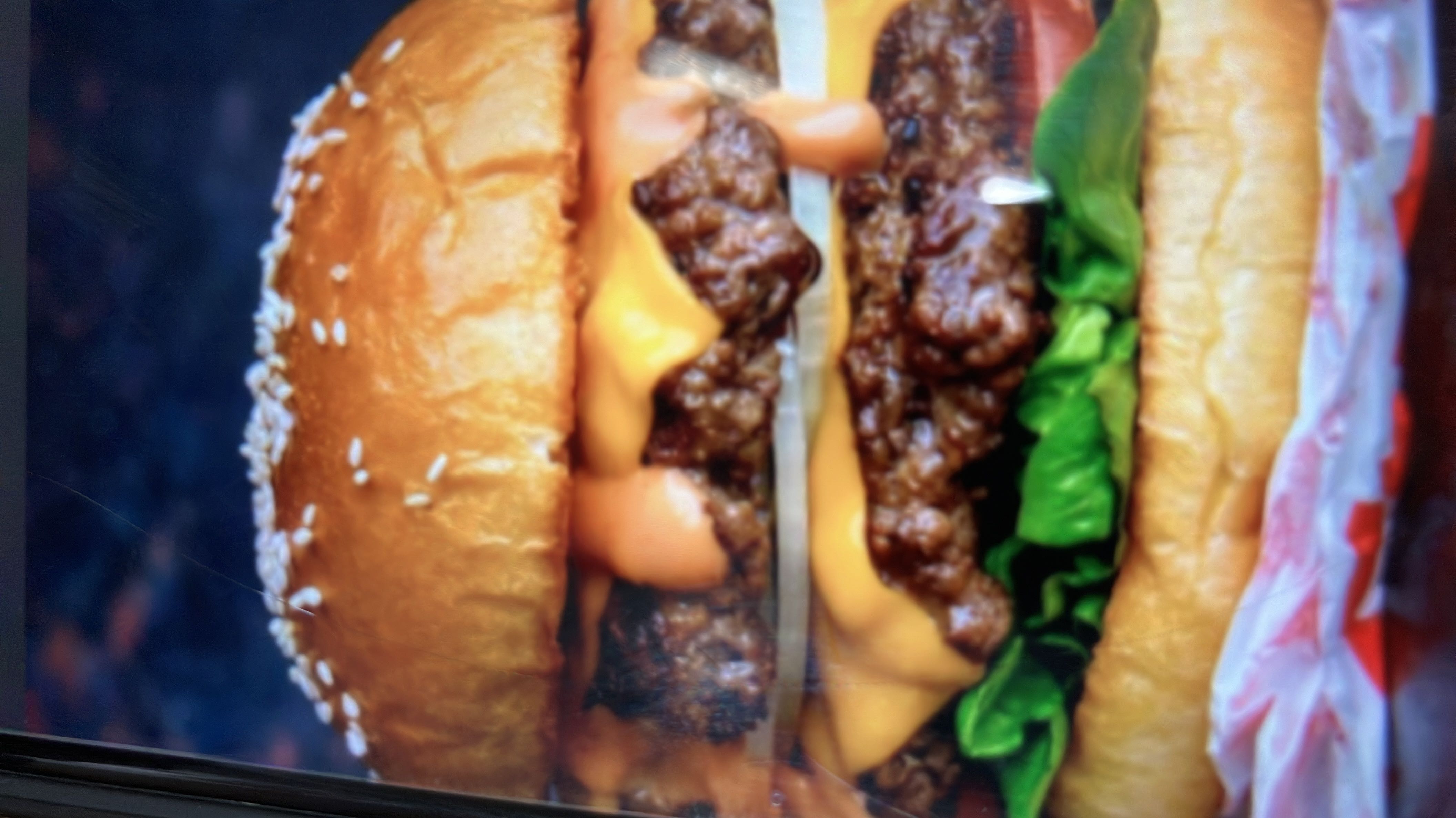 A double cheeseburger with lettuce, sauce, and a sesame seed bun.