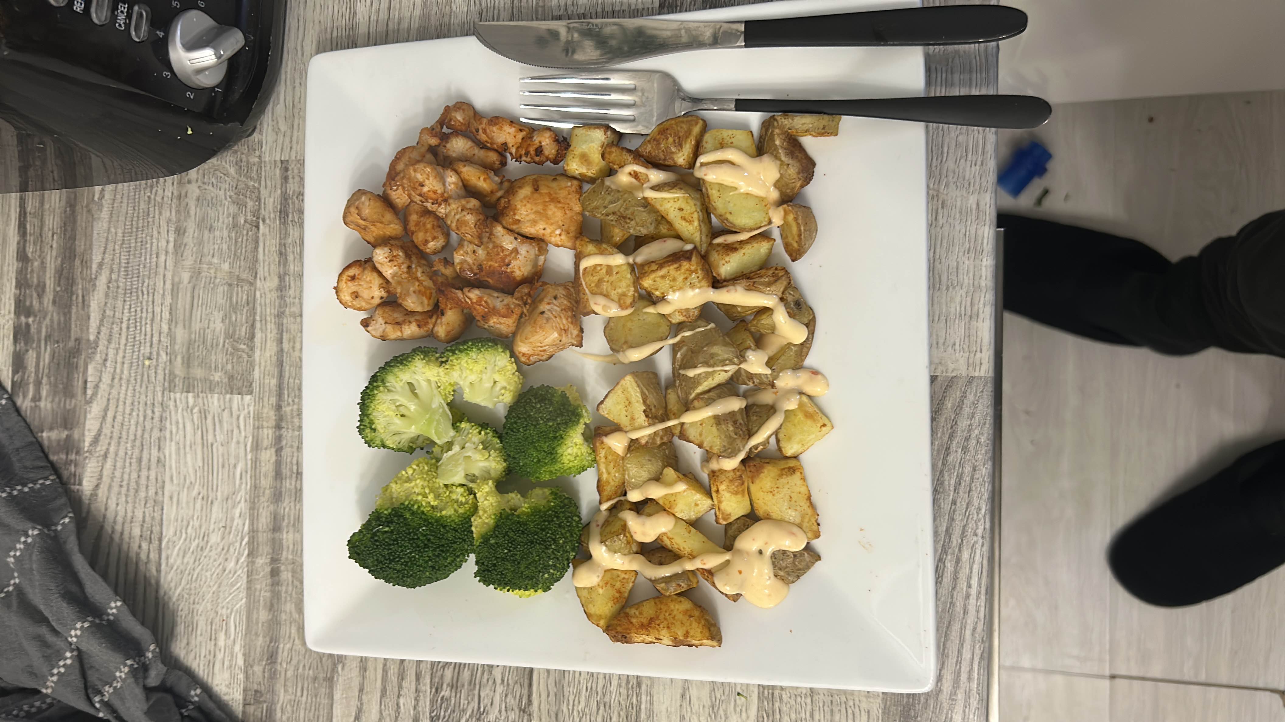 A balanced meal consisting of broccoli, grilled chicken, roasted potatoes, and a drizzle of sauce.