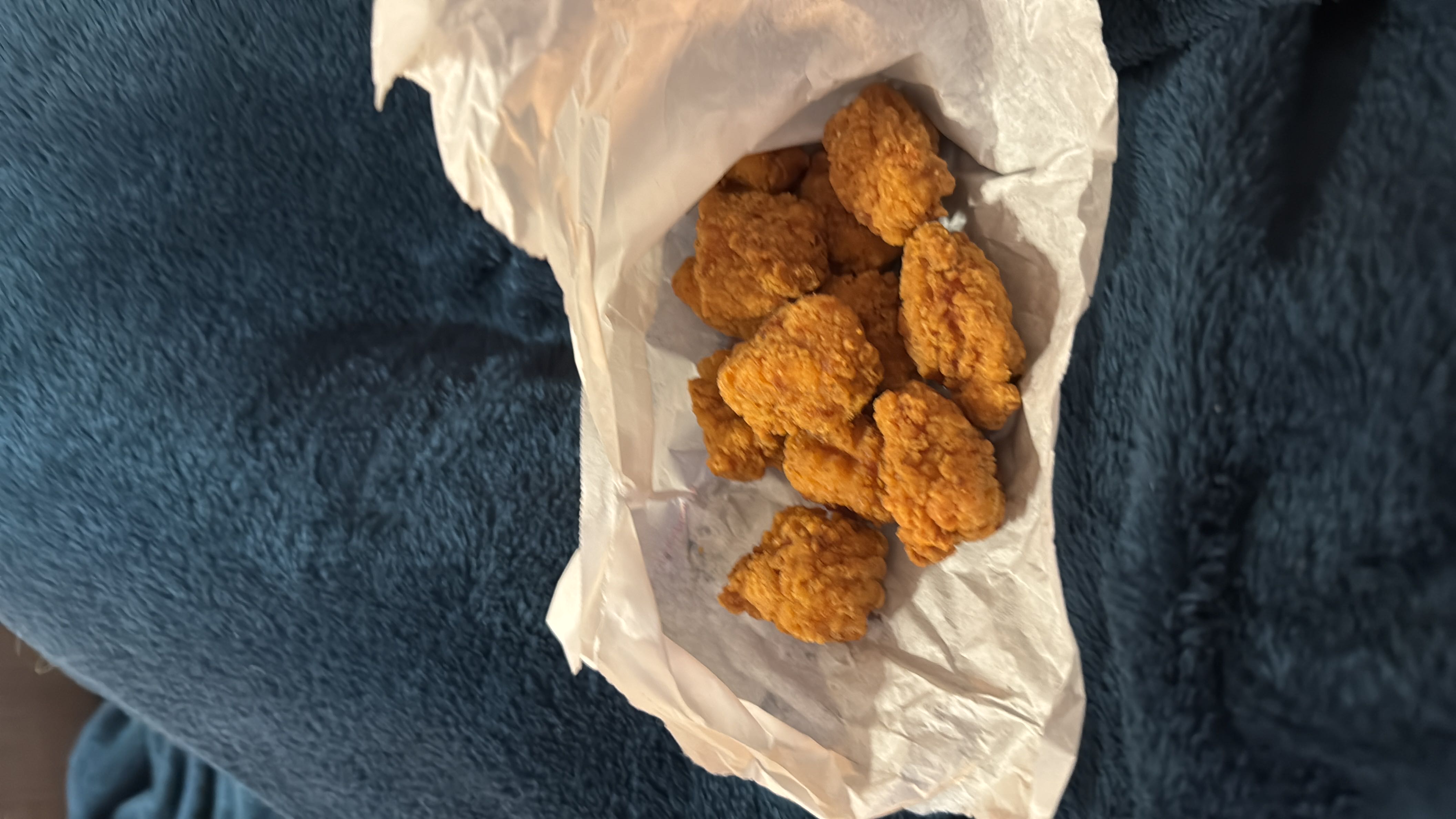 A serving of crispy fried chicken nuggets, high in protein and moderate in fats and carbs.