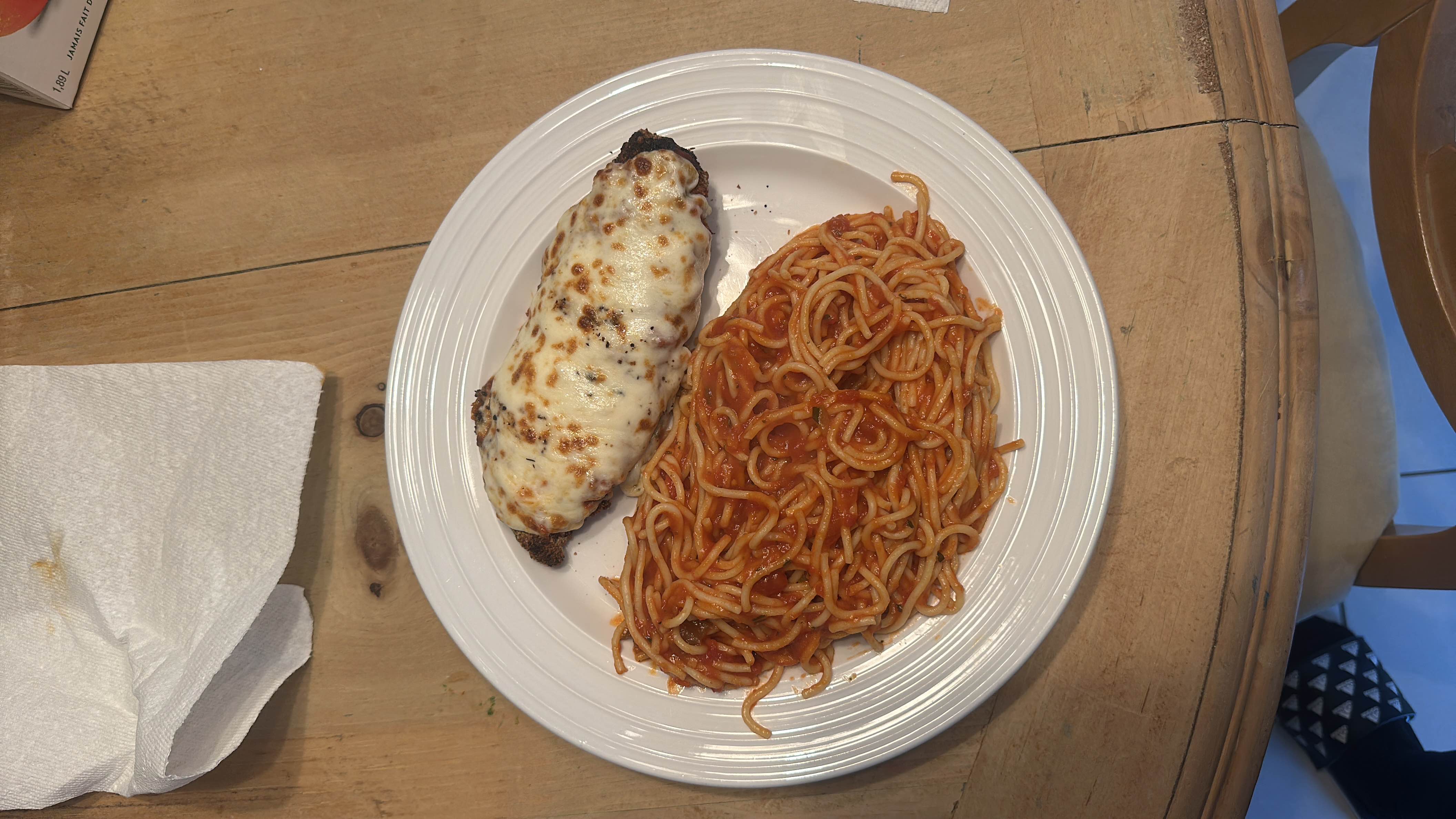 A plate of spaghetti with tomato sauce and a baked chicken breast topped with melted cheese.