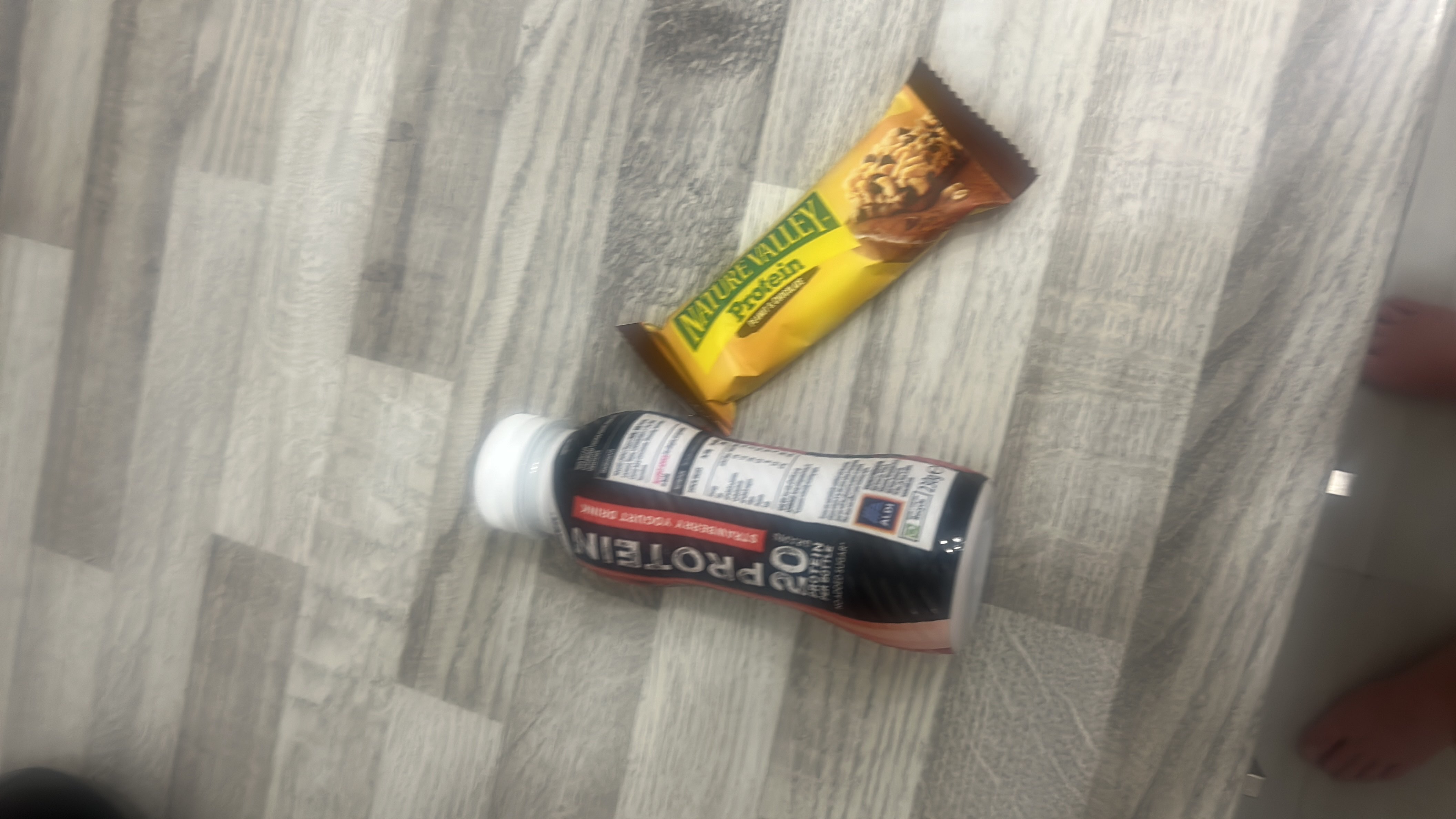 The image shows a protein shake and a protein bar, both of which are high in protein and suitable for a post-workout snack.